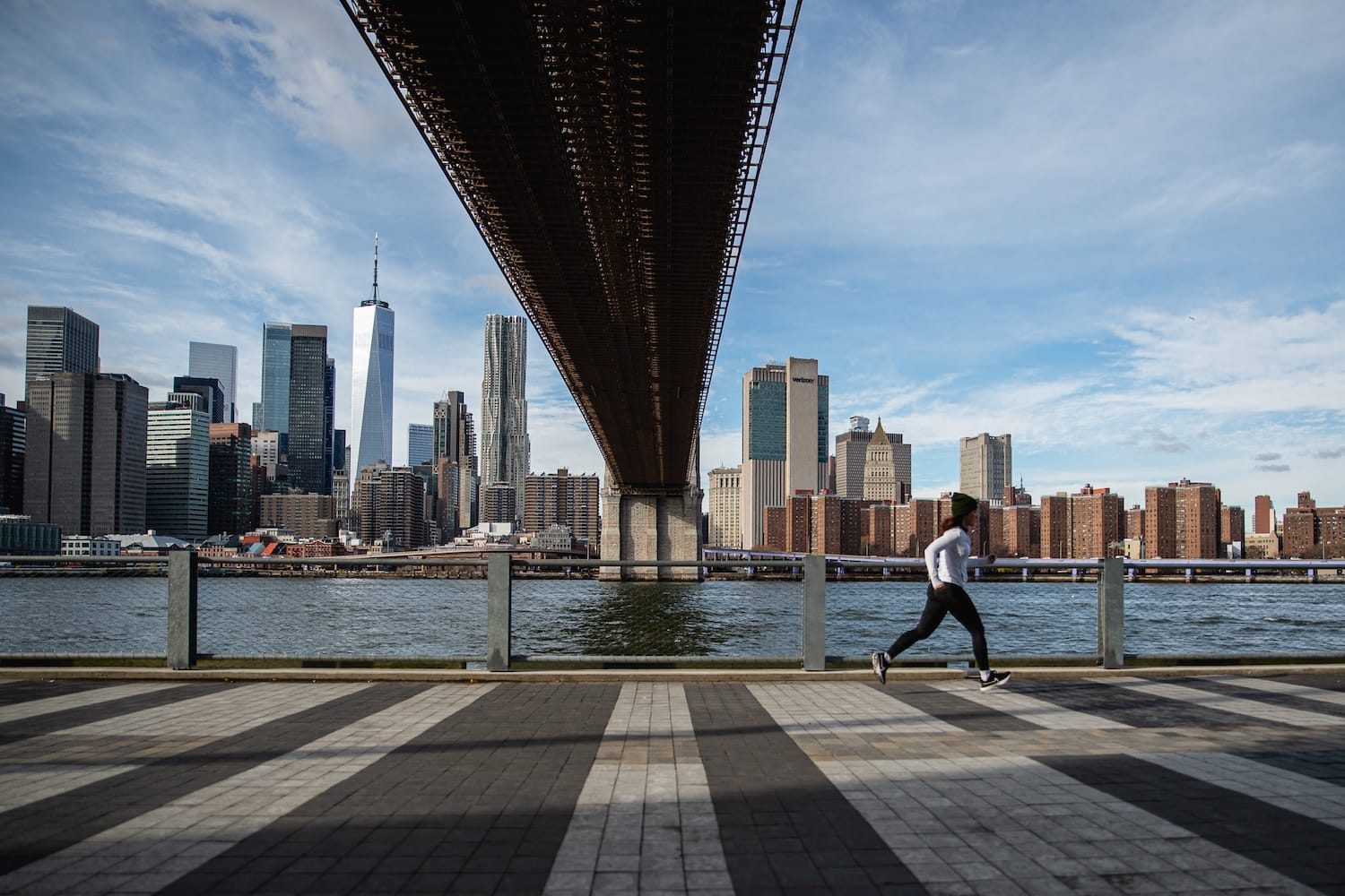 A woman running outside with water and the NYC skyline in the background