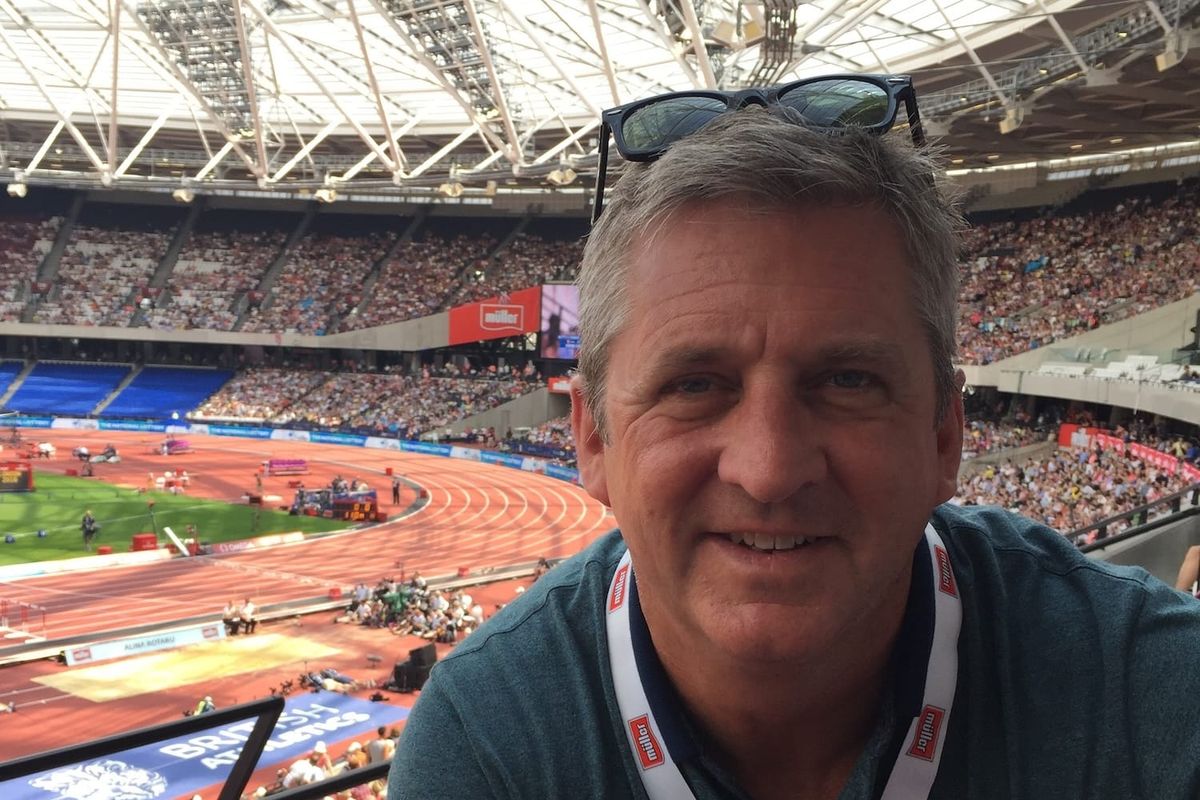 A man in the stands inside a stadium with a track in the background