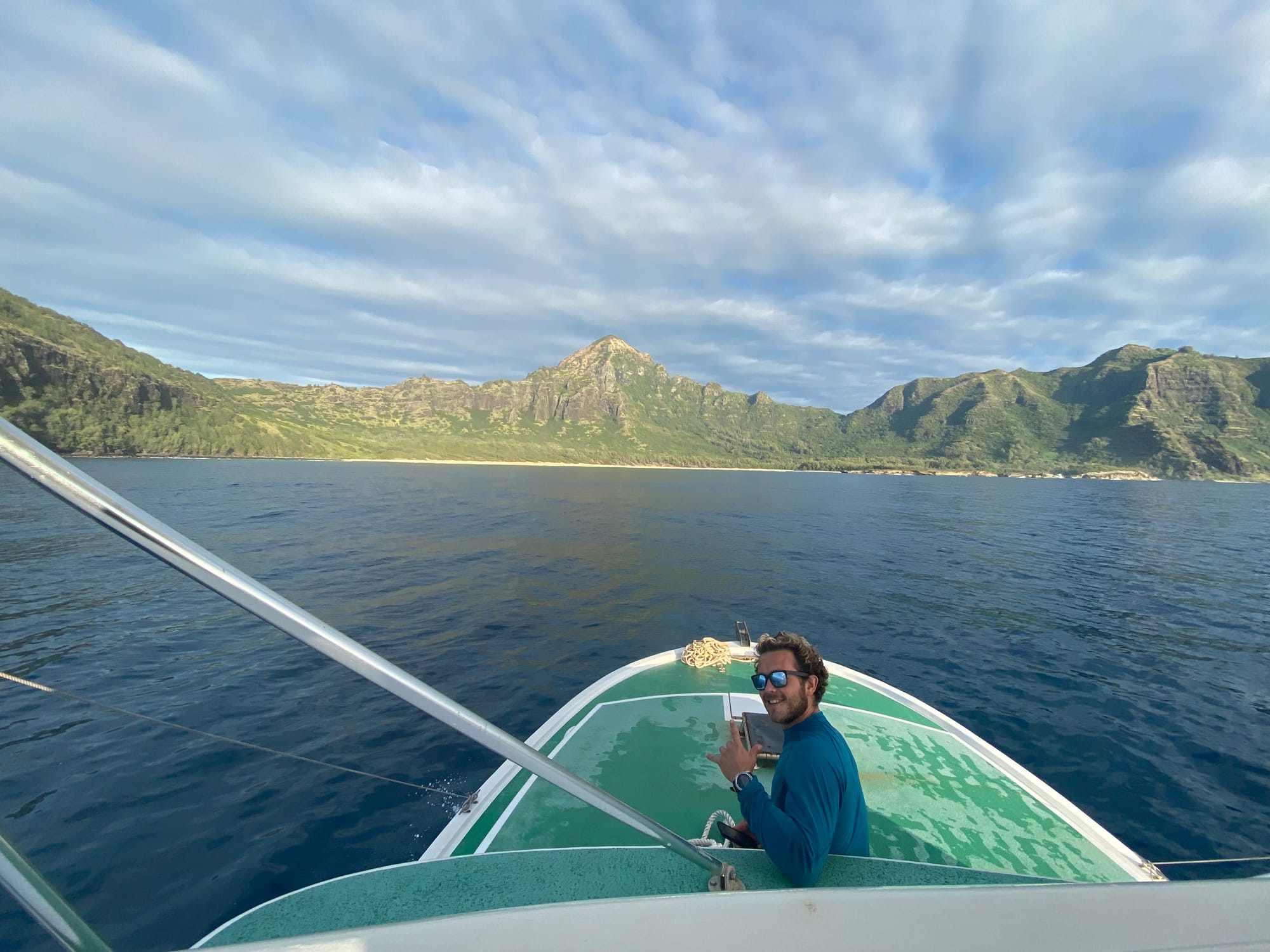 Photo of man on bow of boat off the coast of Hawaii.