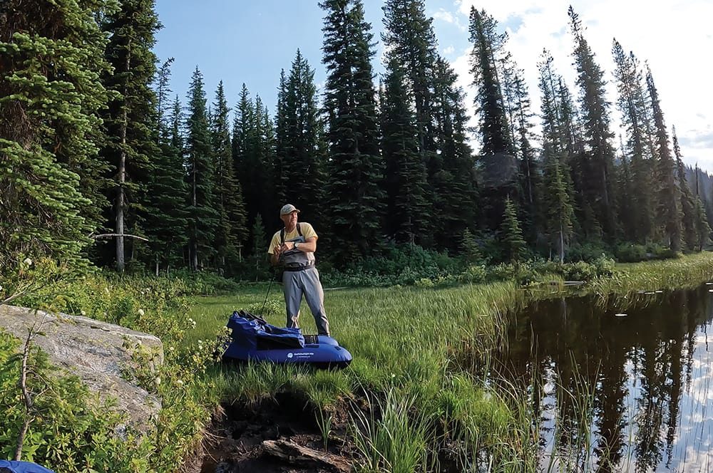 Photo of man fishing from shore on high alpine lake. 