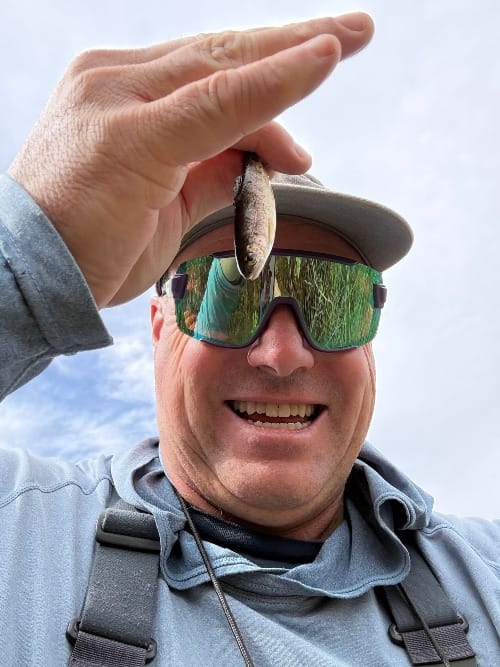 Picture of fisherman holding a small Rainbow trout.