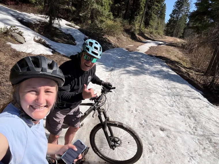 Picture of a boy and girl on their mountain bikes in a patch of snow. 