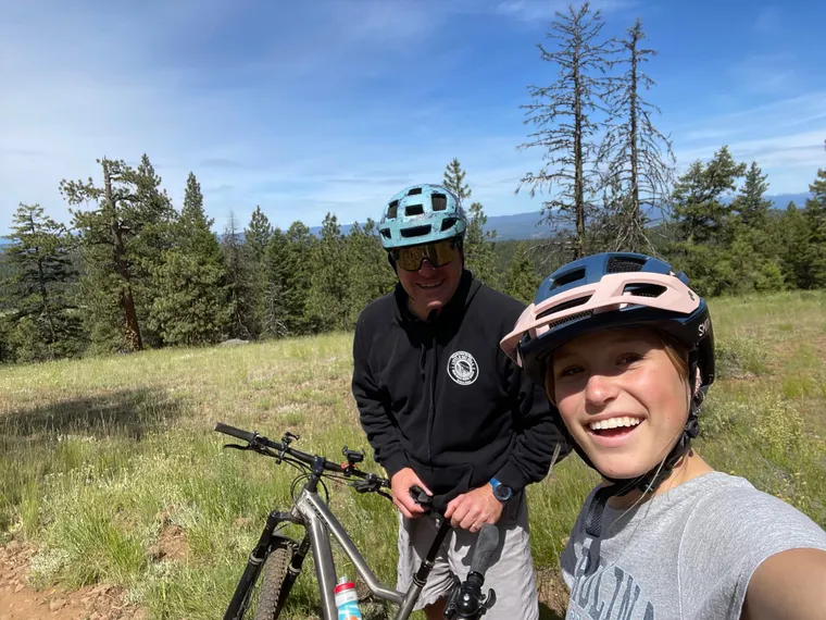 Picture of Dad and daughter mountain biking on top of mountain.
