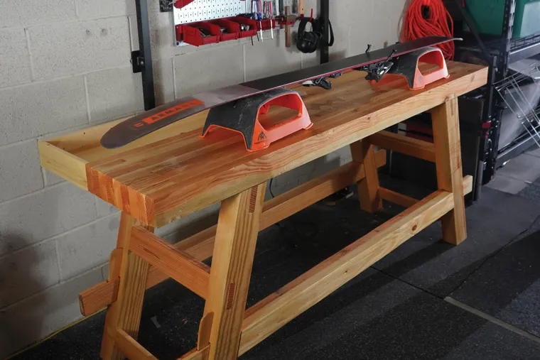Picture of wooden work bench with skis set up and ready to tune on top. 