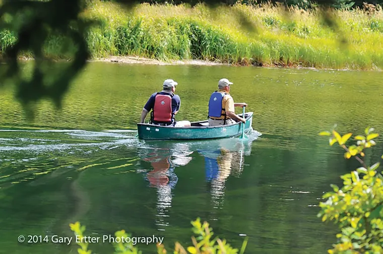 Picture of two men paddling a canoe on the river.