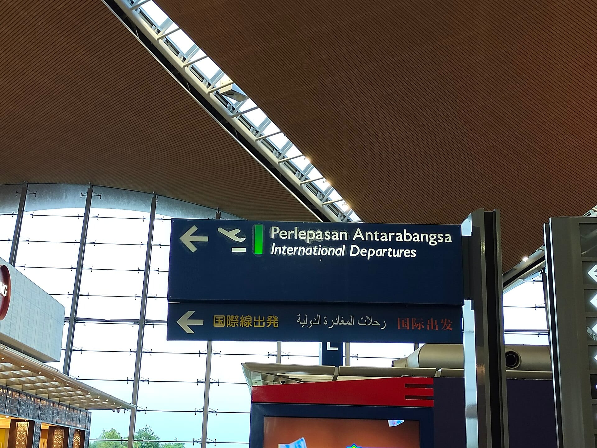 International departures signs beneath the sweeping ceiling of Kuala Lumpur International Airport Terminal 1.