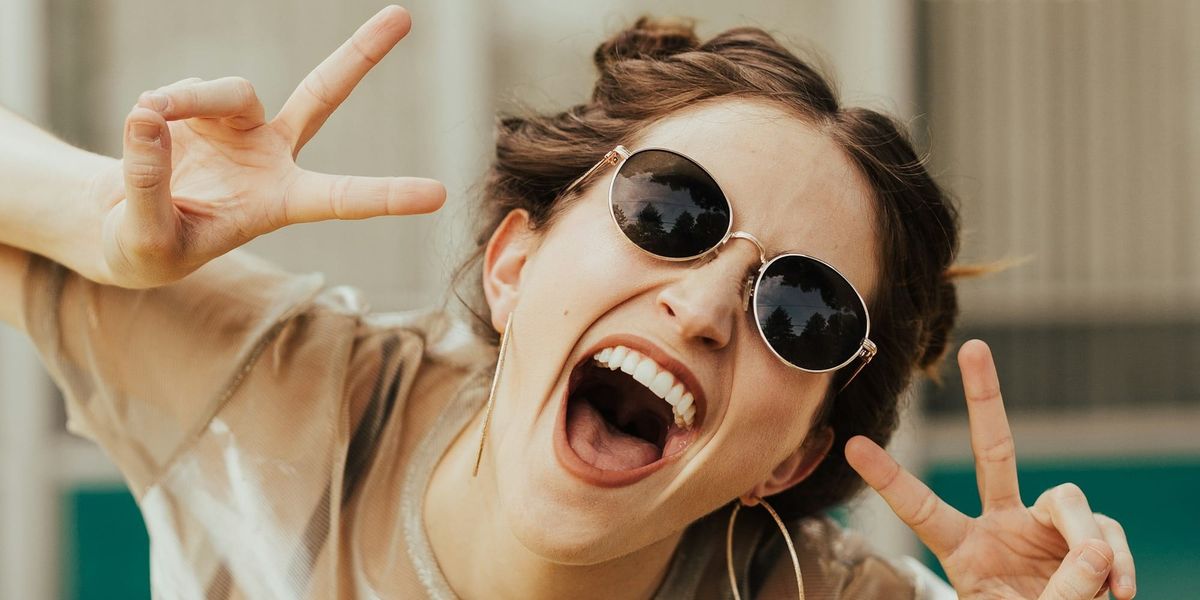 一個戴墨鏡的西方女生開心地對著鏡頭扮鬼臉比YA