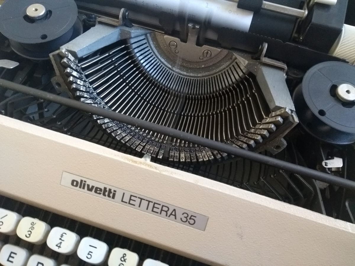 Close-up photo of the mechanism of a typewriter, with a small amount of the body and keyboard visible.