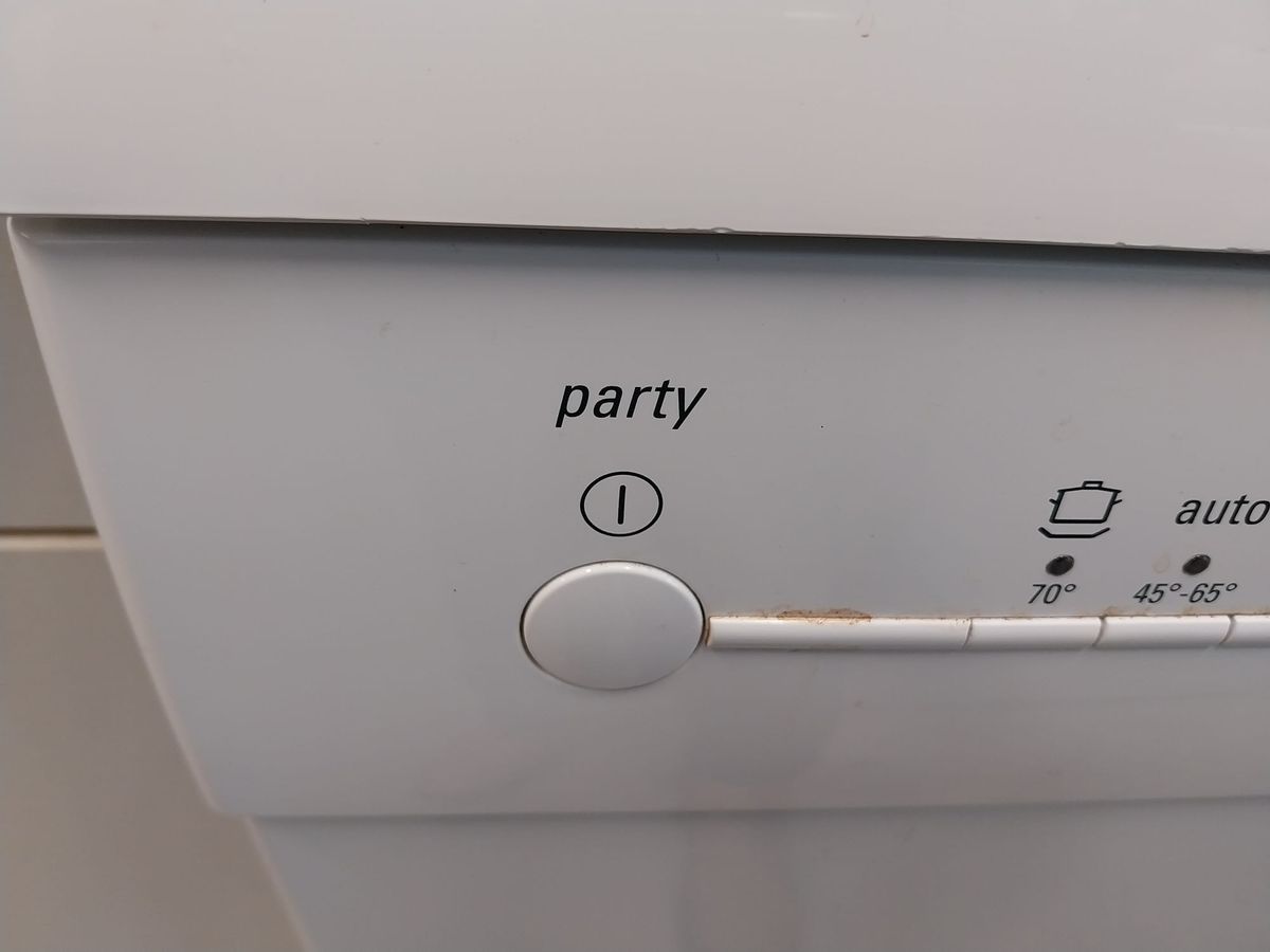 Close-up of the front panel of a dishwasher. Over the power button, there is a label which says "party."