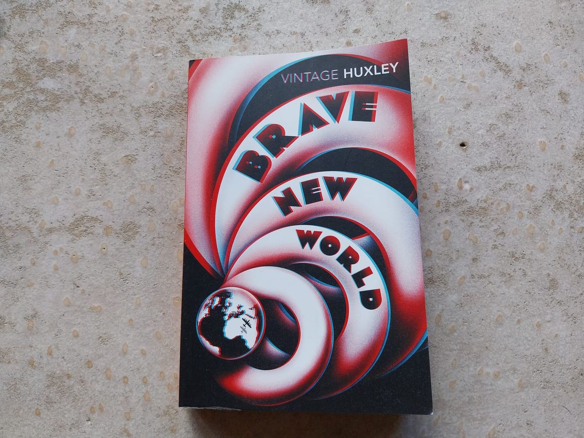 A book on a concrete floor. It's Brave New World by Aldous Huxley, and has an image of a spiral which culminates in a stylized earth.