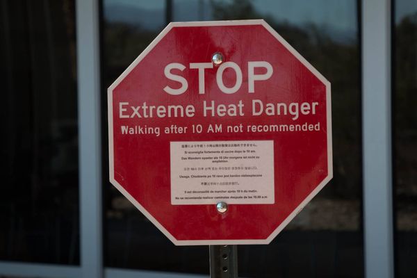 A red stop sign with a warning in several languages. "Stop: Extreme Heat Danger. Walking after 10AM not recommended."