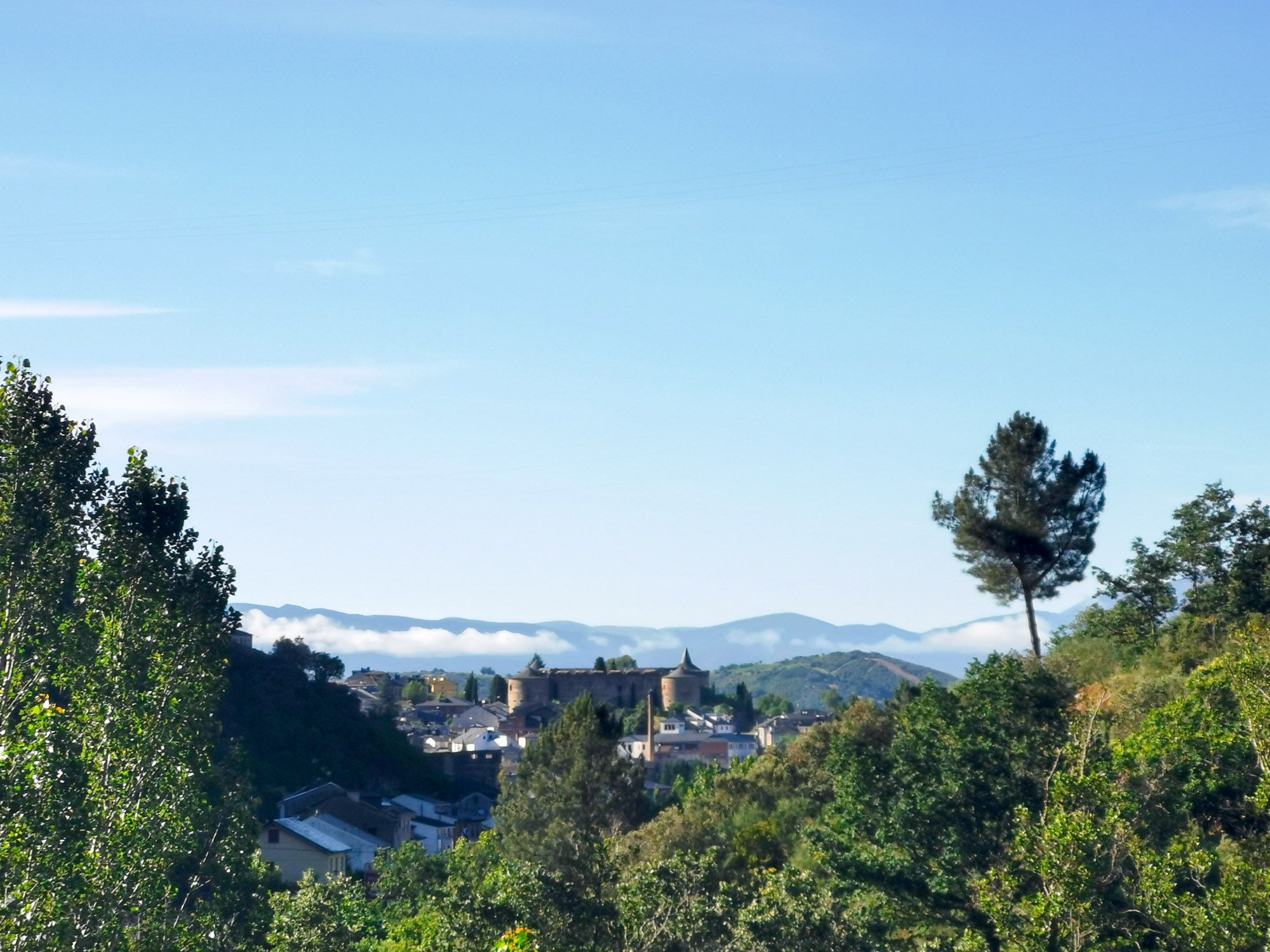 เมืองอยู่ในหุบเขา เห็นอาคารโบสถ์ และเมฆขายปุย ๆ อยู่ด้านหลัง