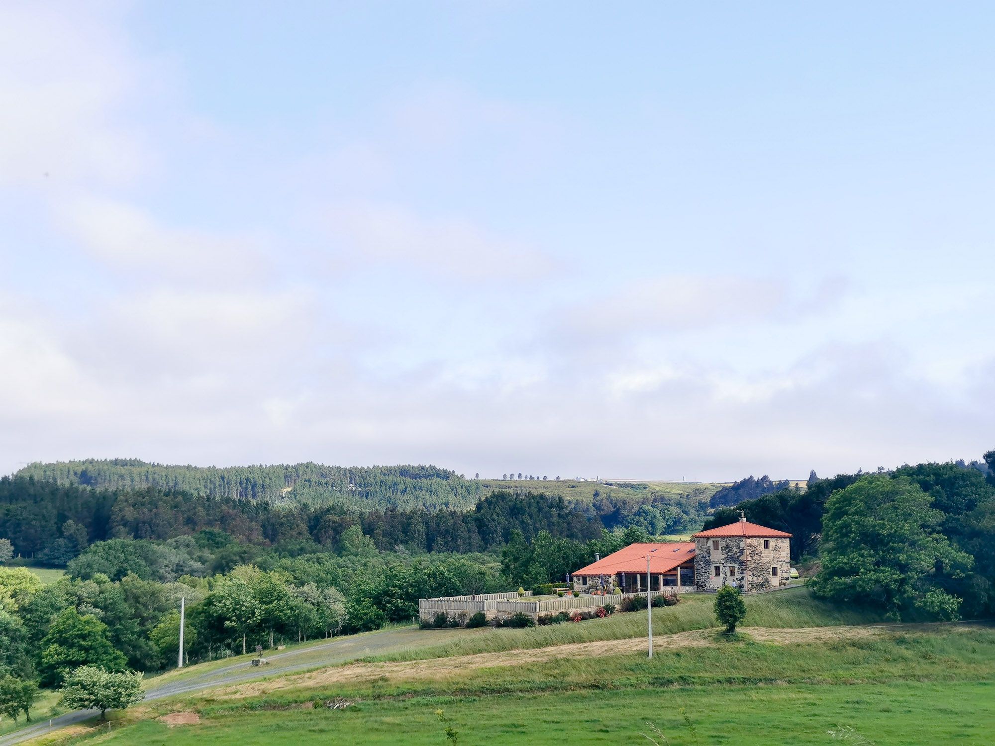 ตึกสร้างด้วยหิน อยู่กลางทุ่ง มี backdrop เป็นป่า และเนินเขา