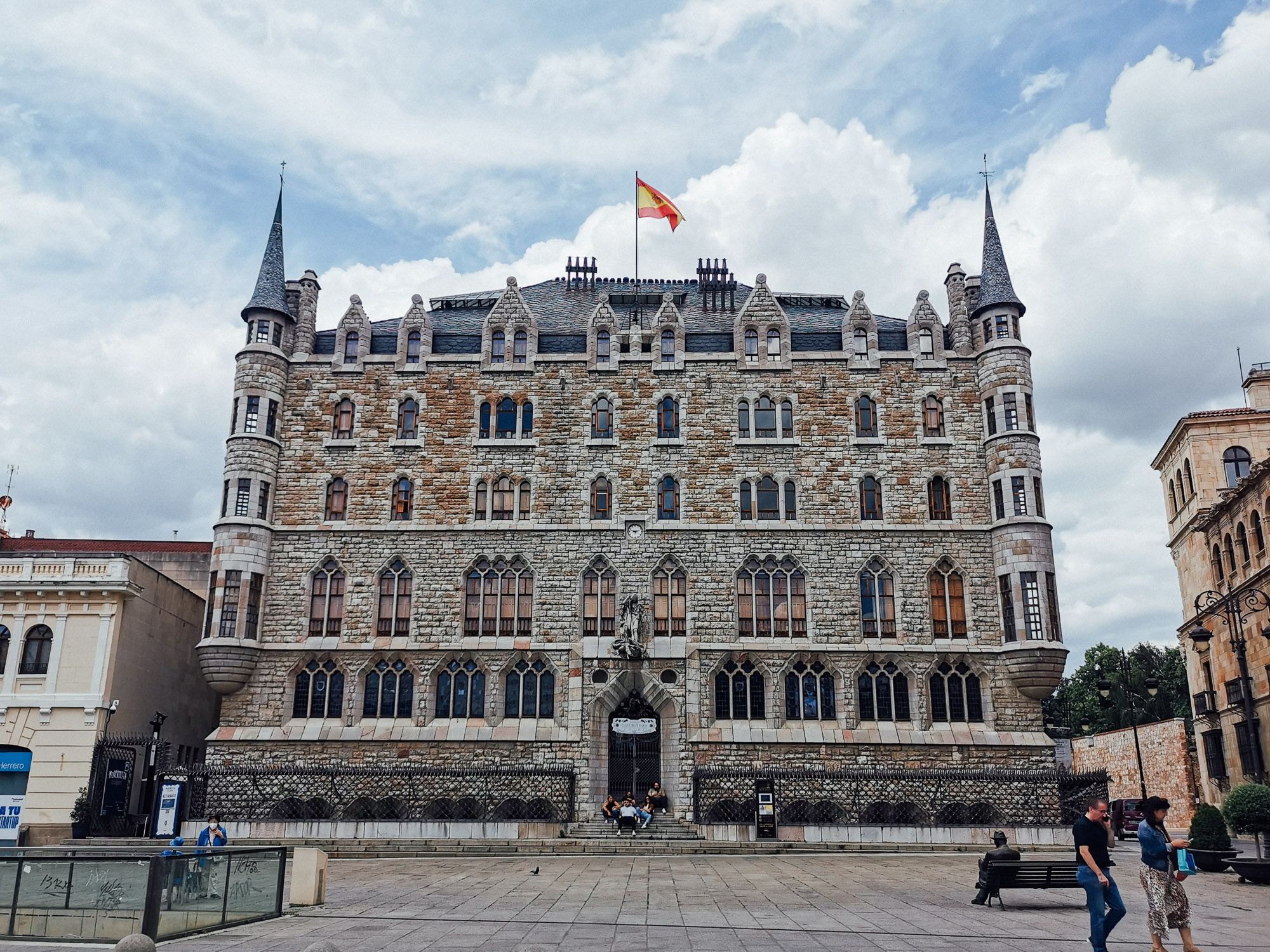 ด้านหน้าของ Casa Botines มุมขวาของรูปมีรูปปั้นของ Gaudi นั่งวาดรูปอยู่บนม้านั่ง