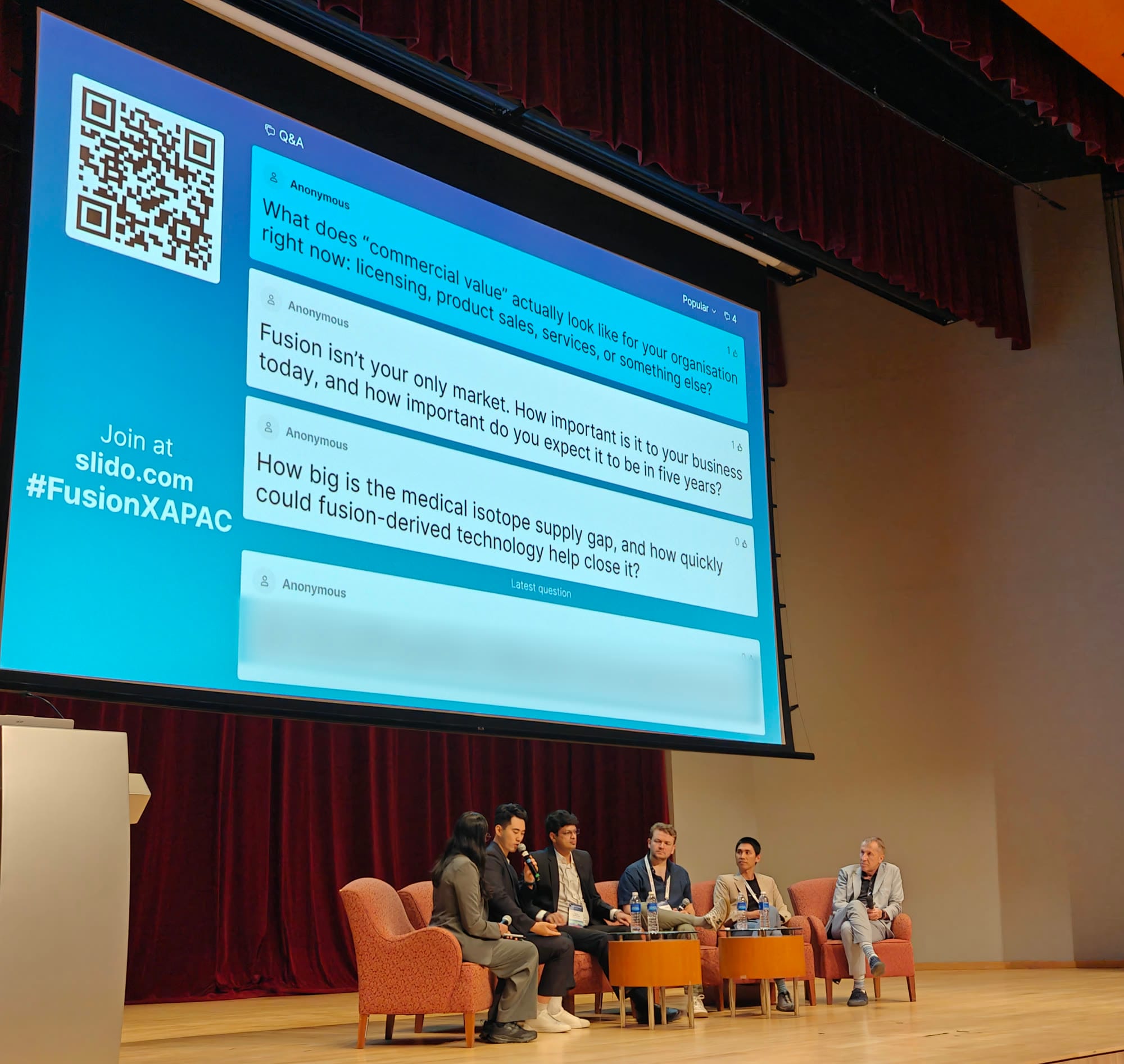 Audience questions on screen during the Fusion-Derived Innovation panel at FusionX:APAC 2026, including "Fusion isn't your only market" and one on the medical isotope supply gap
