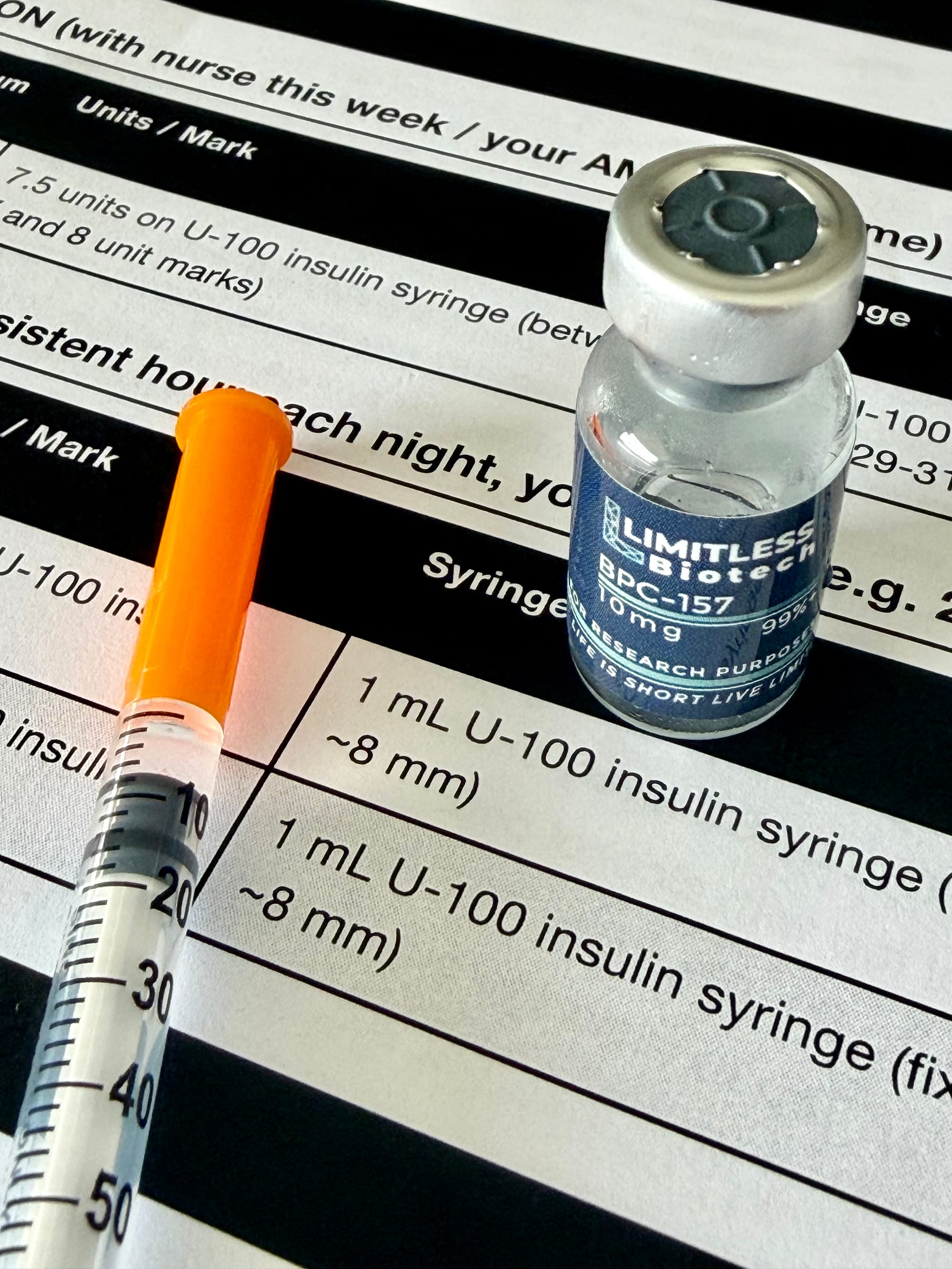 BPC-157 vial and insulin syringe on the printed protocol summary