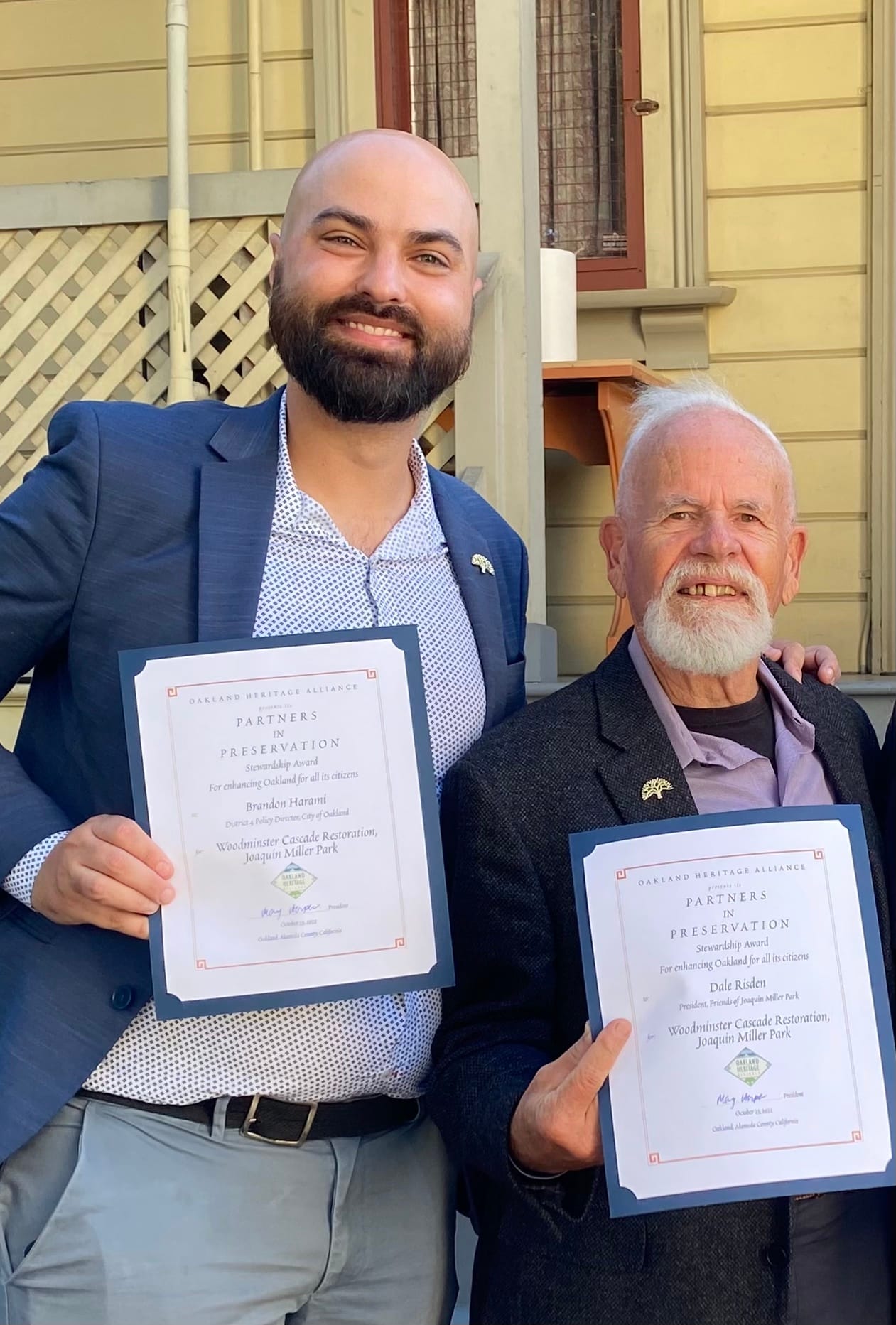 Brandon Harami stands next to Dale Risden as they display their Oakland Heritage Alliance awards in 2022.