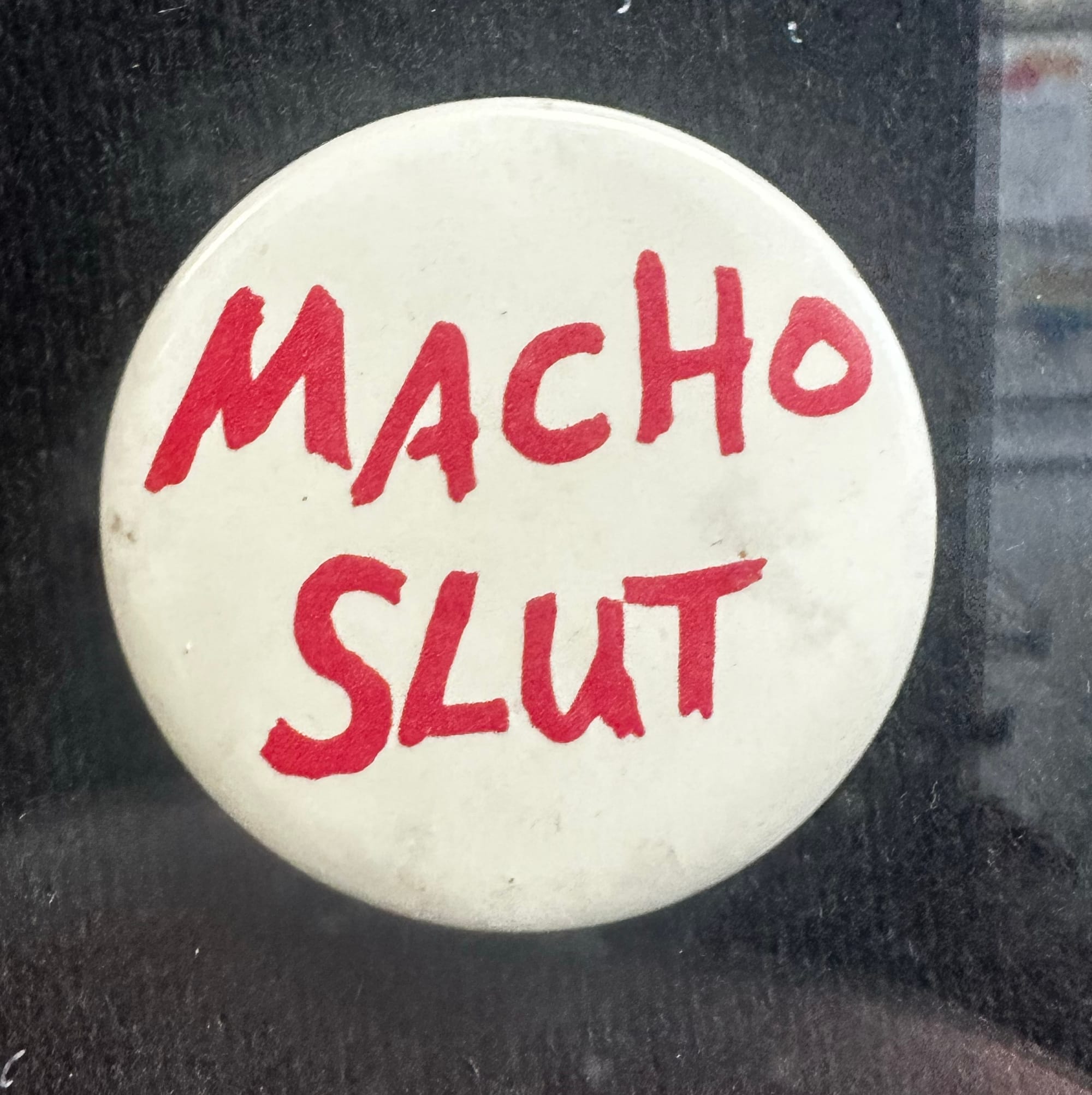 A pin reading "MACHO SLUT"