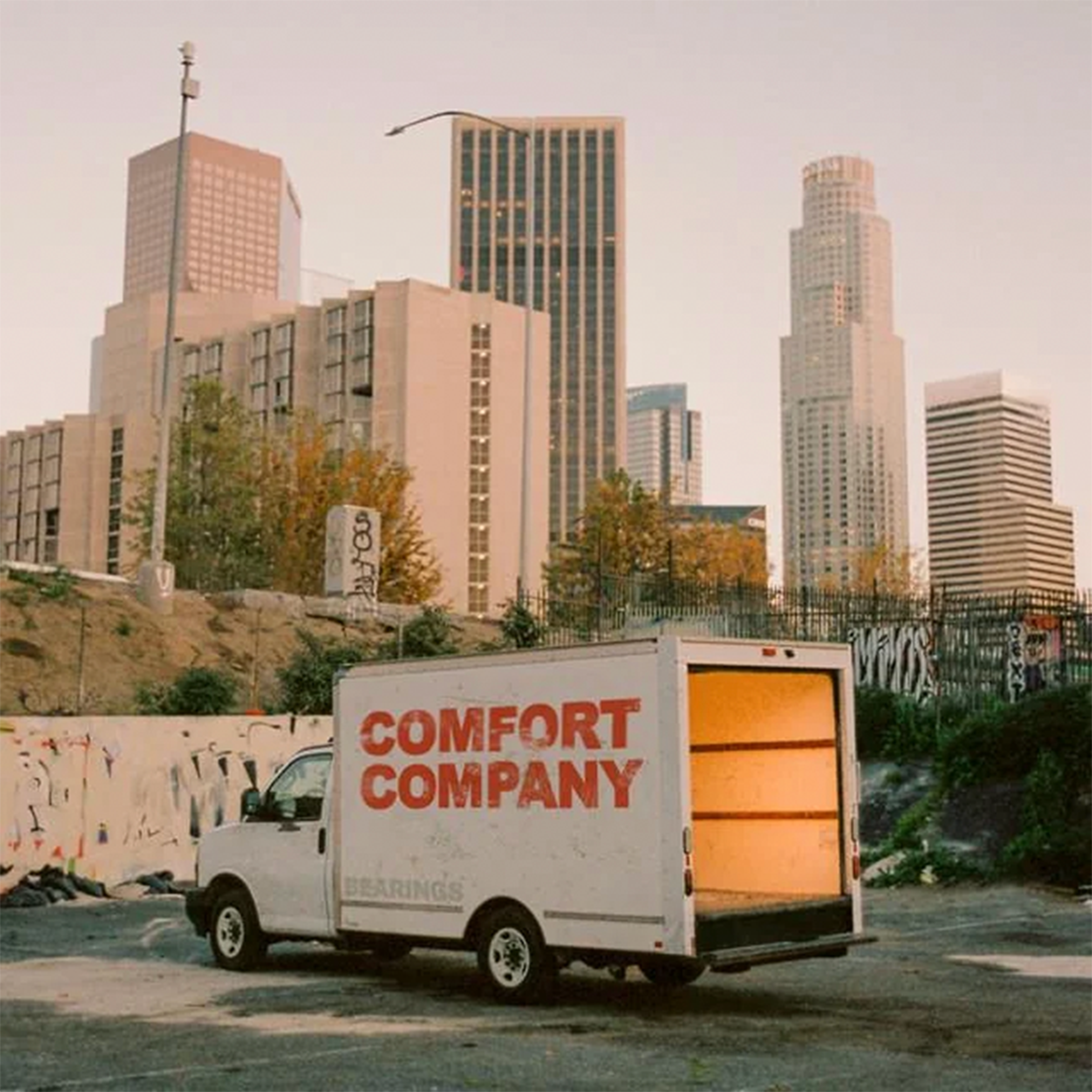 The cover of Bearings' "Comfort Company" depicting a moving truck with the title on the side in front of a downtown skyline