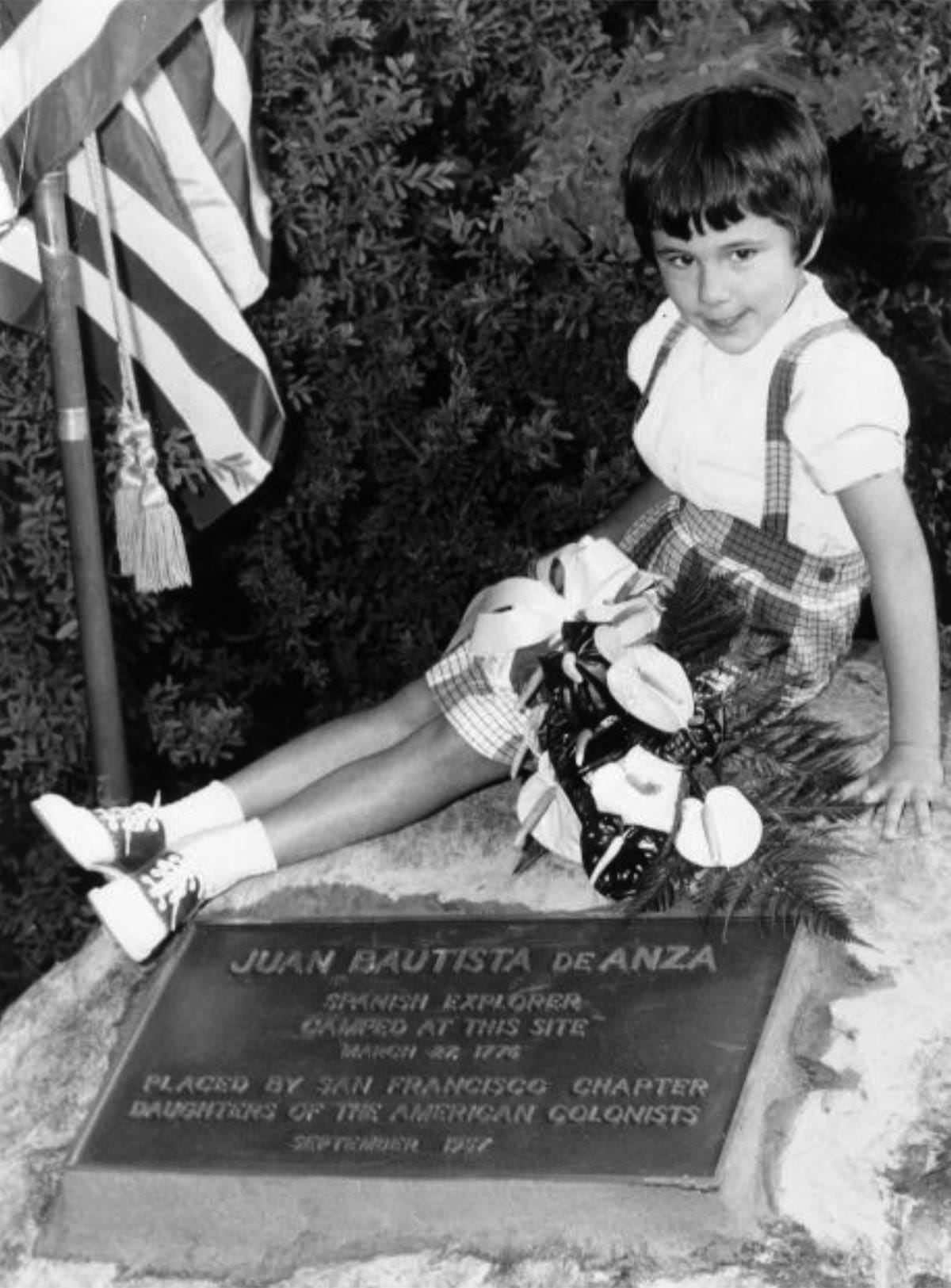 girl sitting next to de Anza plaque