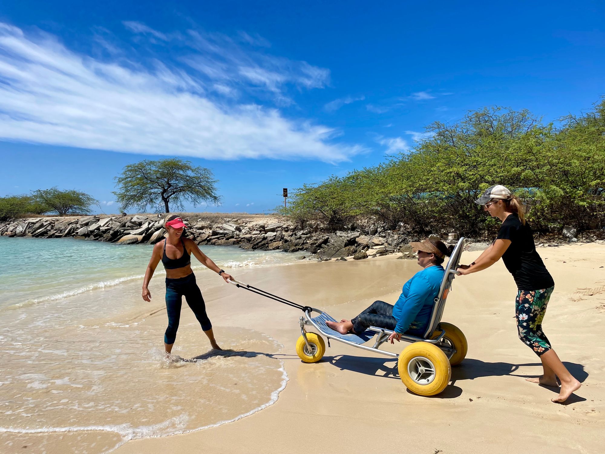 Disabled woman entering the beach in a beach wheelchair