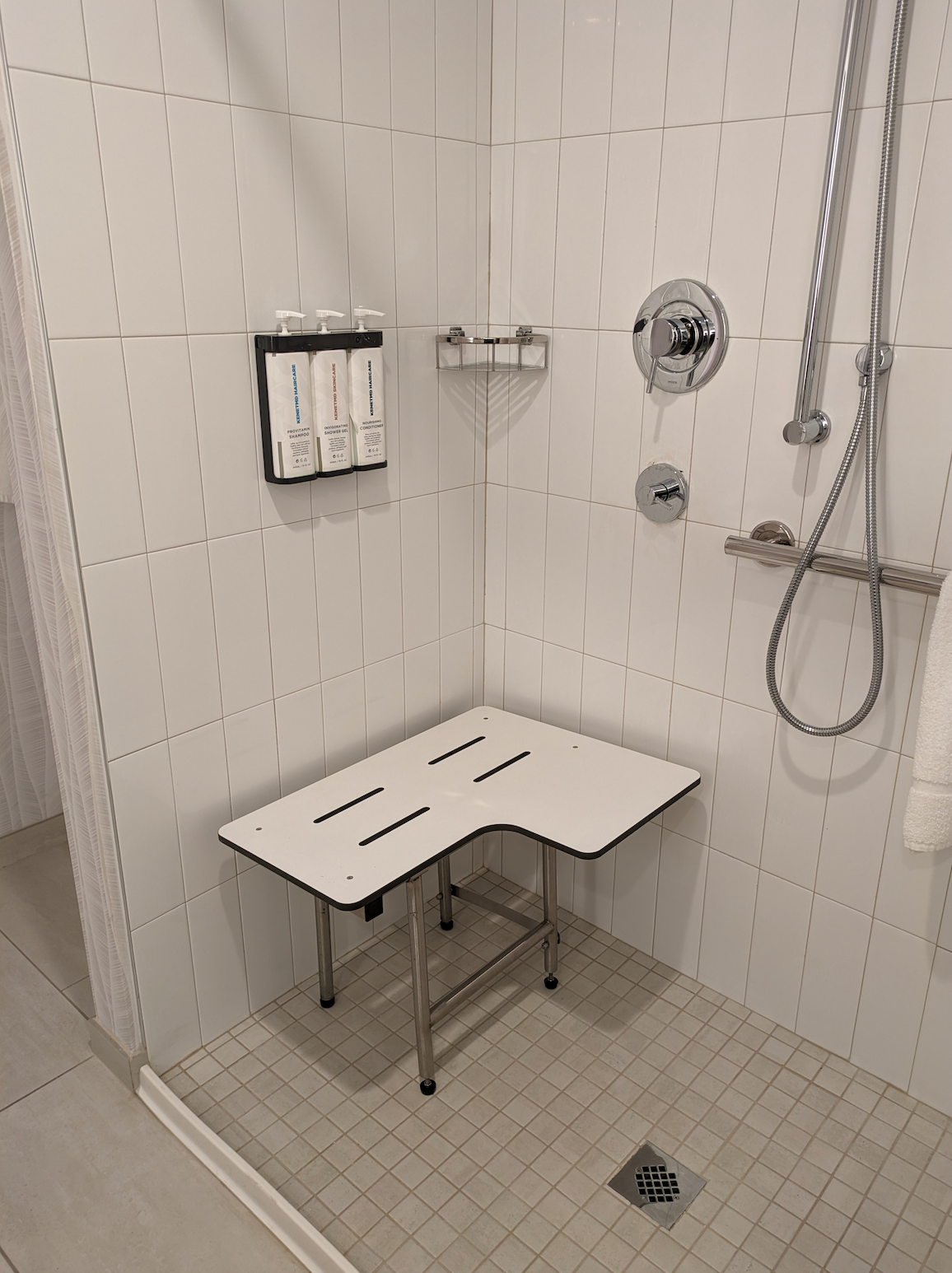 Step-in shower with a seat, grab bars, and handheld showerhead