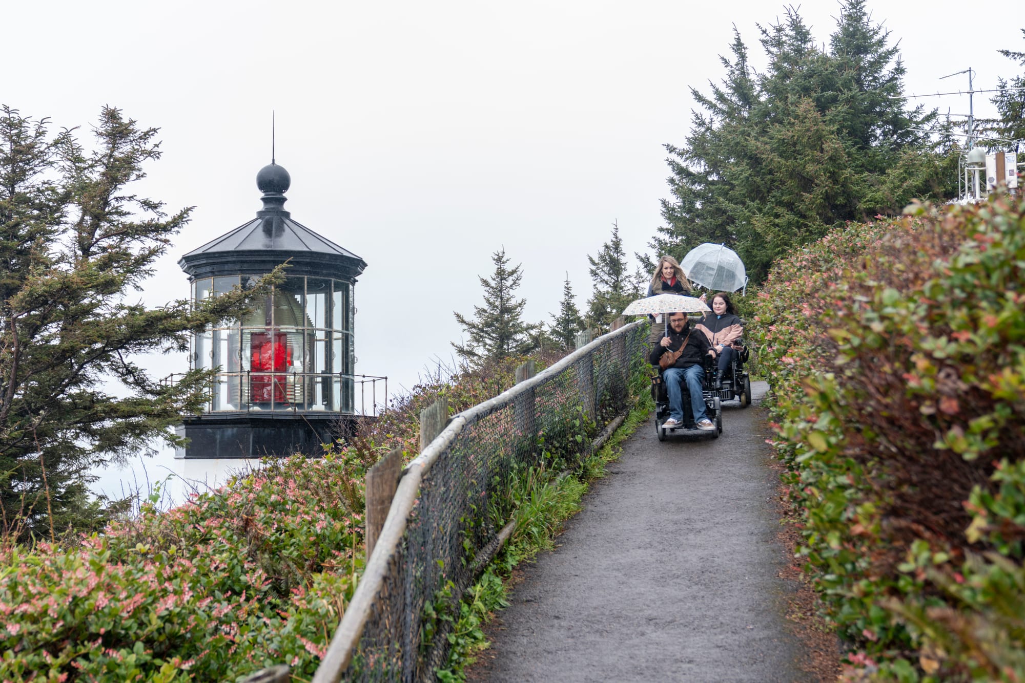 Two wheelchair-users going down the trail to Cape Meares Lighthouse on the Tillamook Coast
