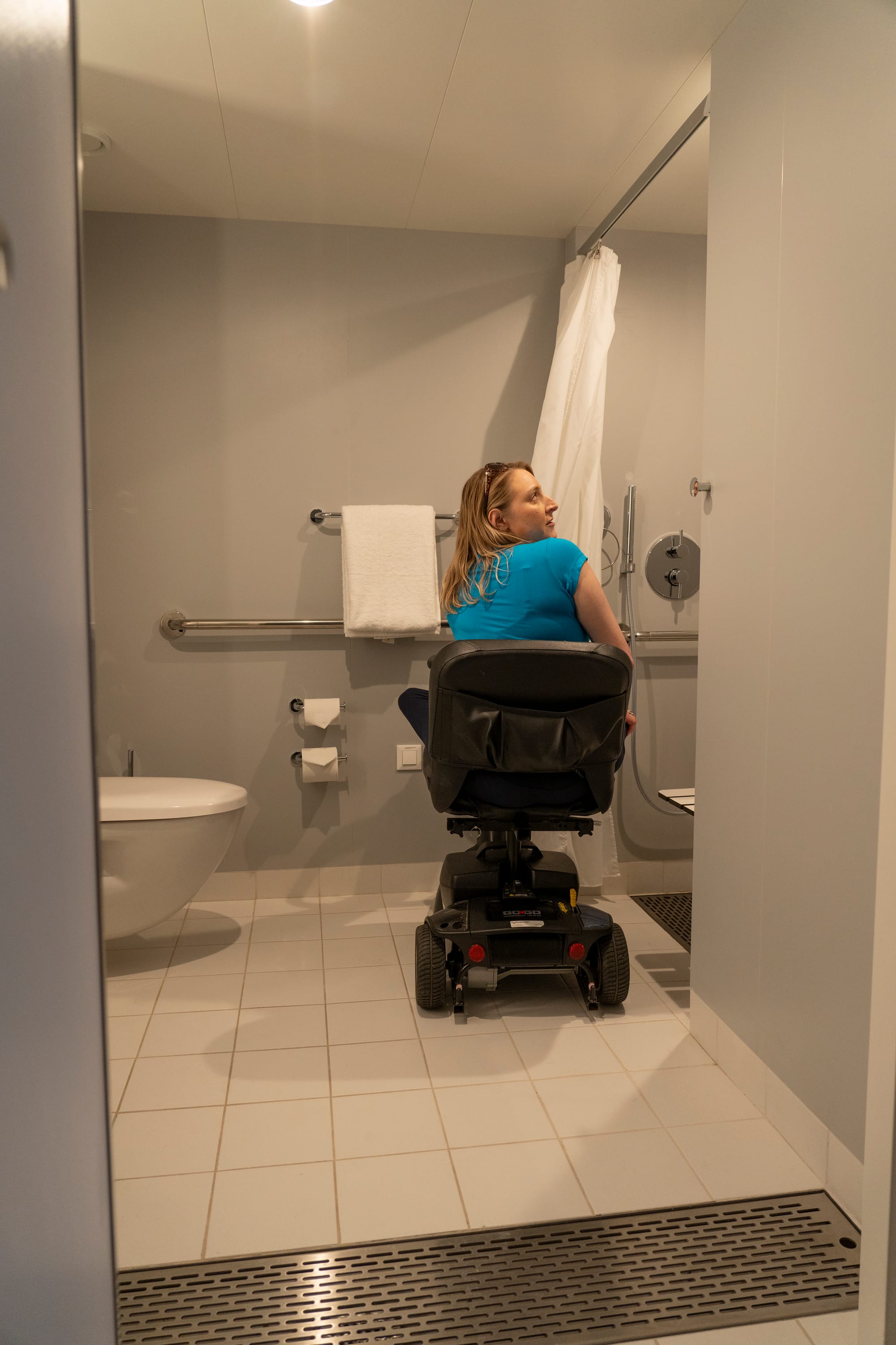 Anna, a wheelchair user, inside her Virgin Voyages cabin bathroom with a roll-in shower