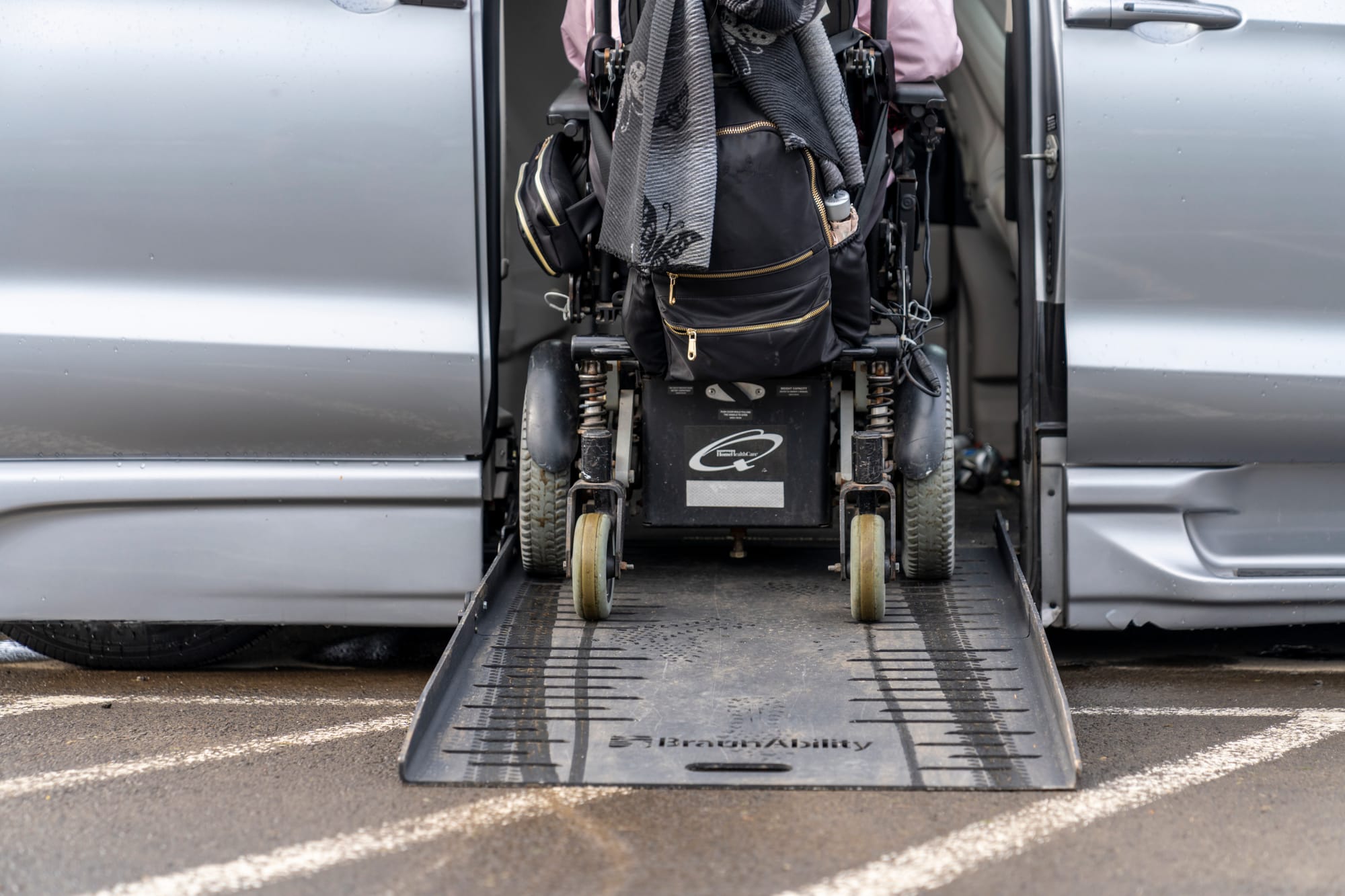 Wheelchair user rolling up a ramp into an adaptable van