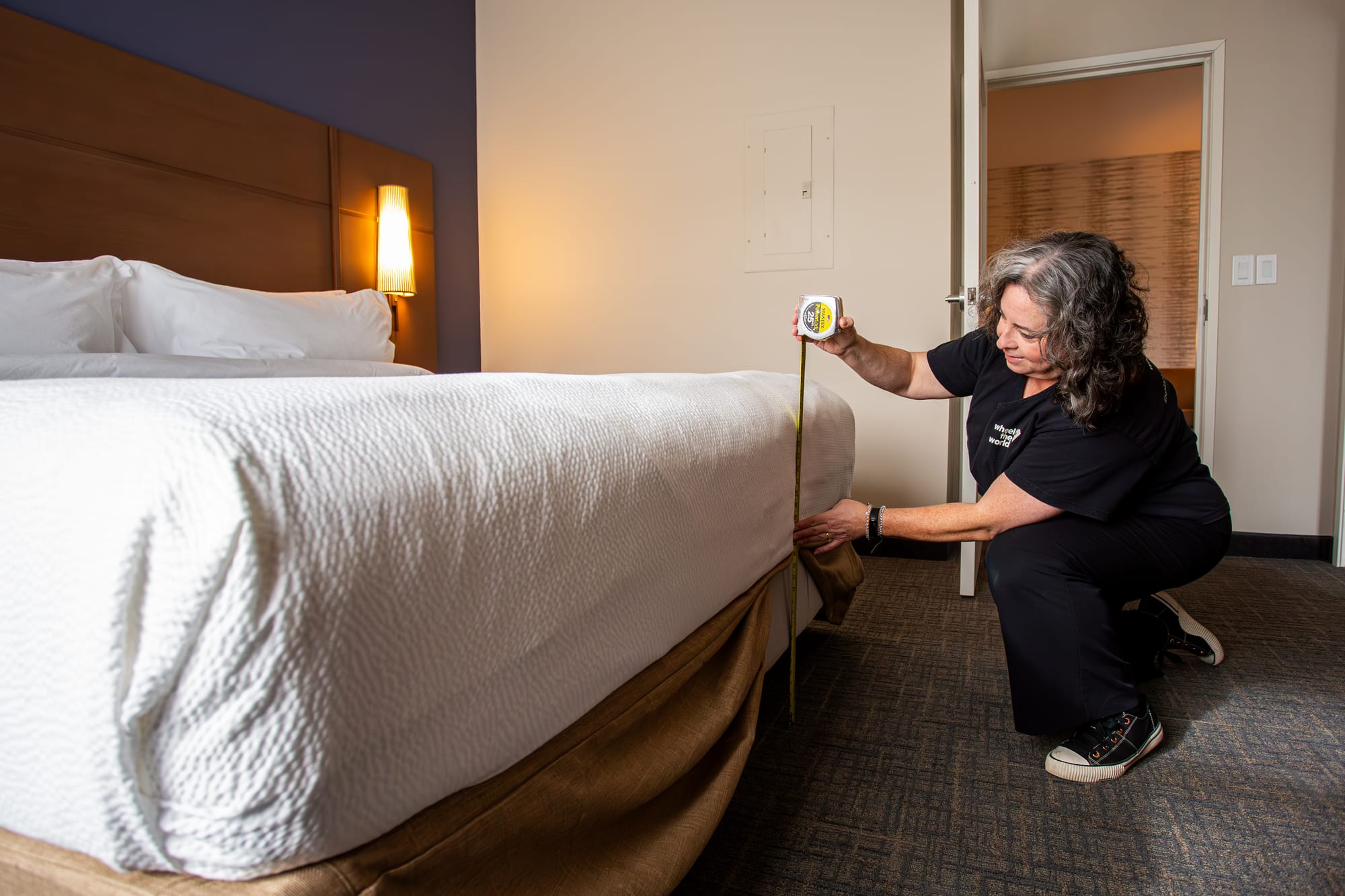 Wheel the World mapper measuring bed height in a hotel room