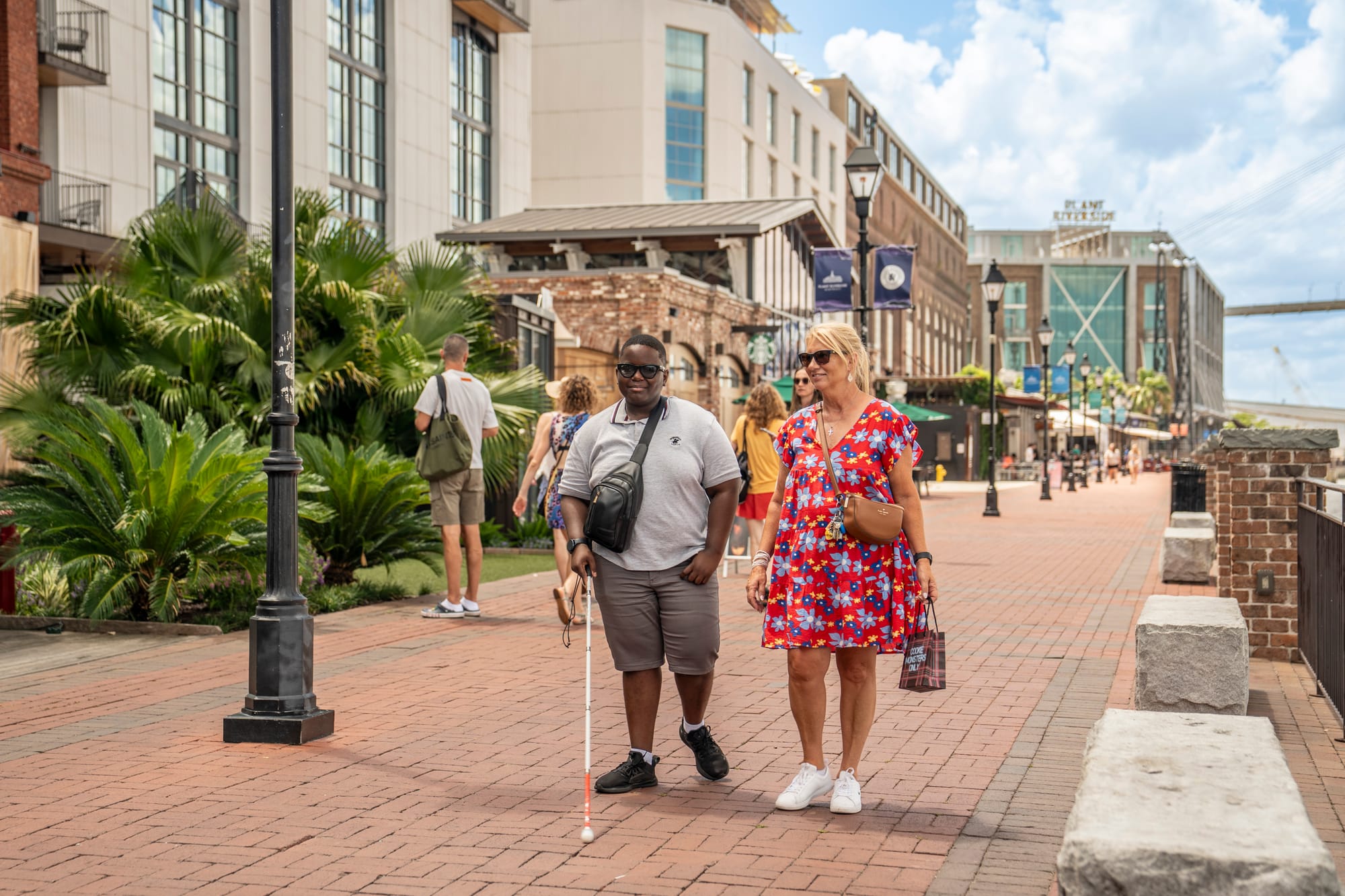 Blind person and companion walking riverside in Savannah, GA