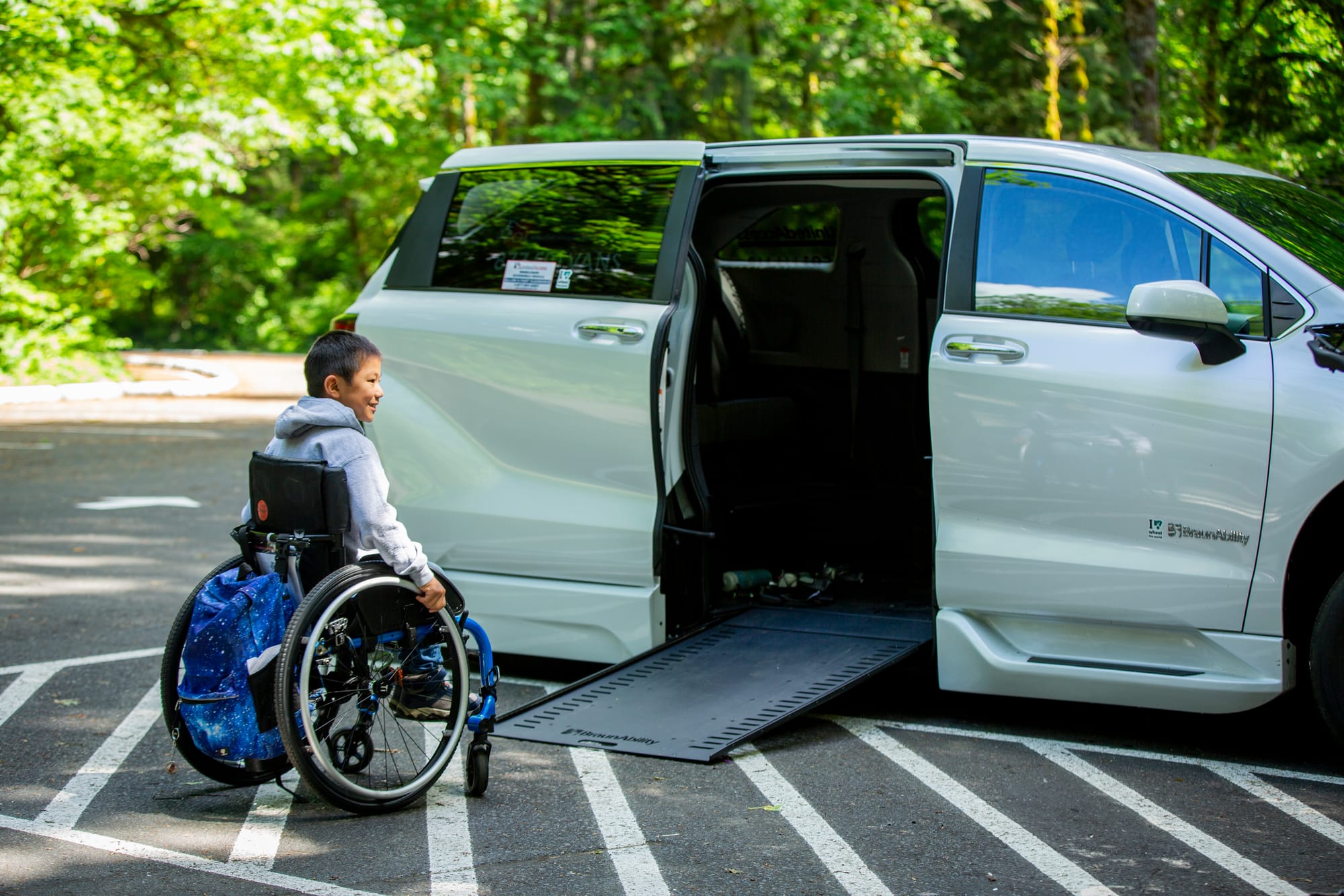 Wheelchair user boy going up a ramp into an adapted van