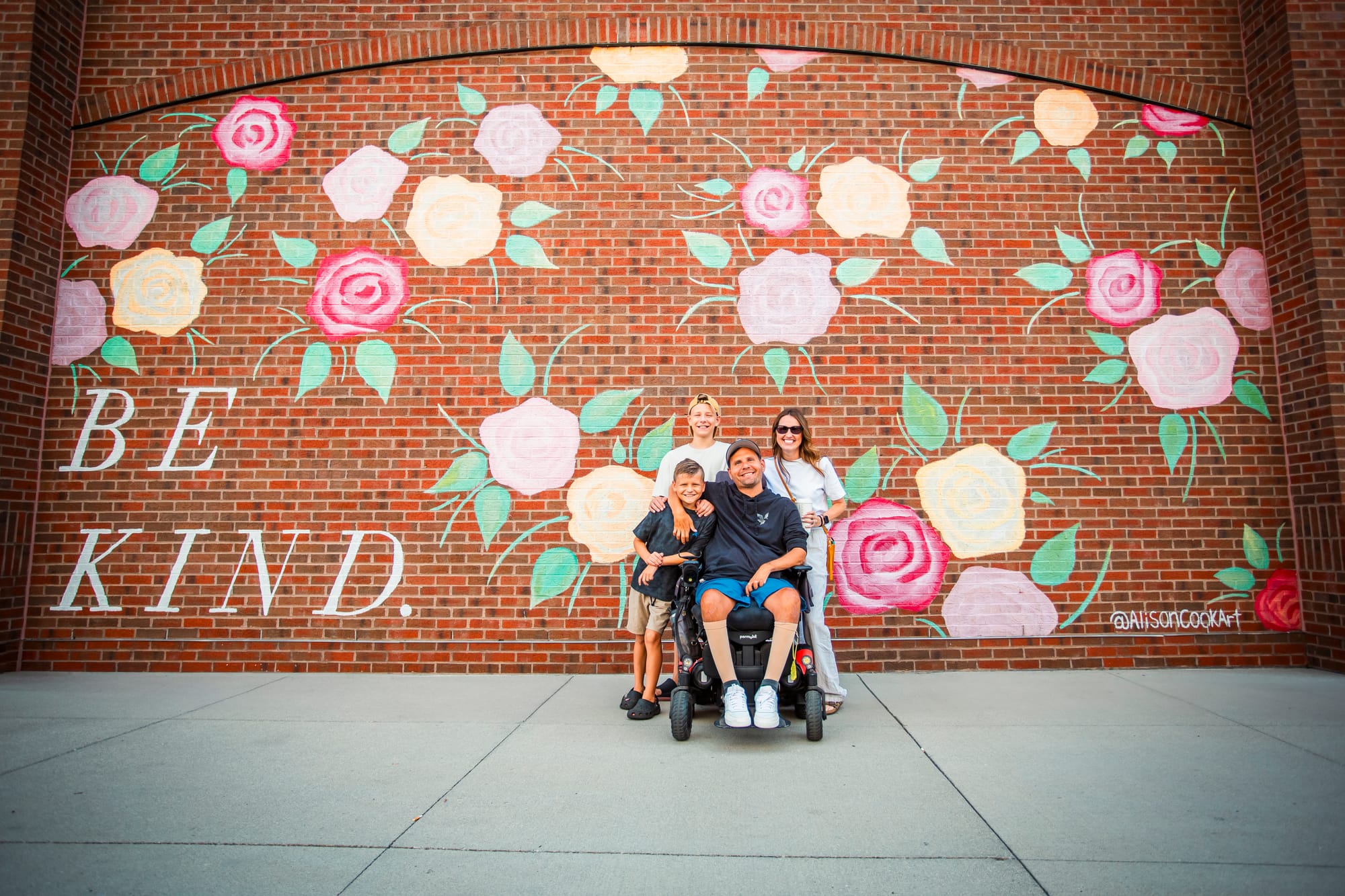 Wheelchair user and family at the "Be Kind" mural at Liberty Center