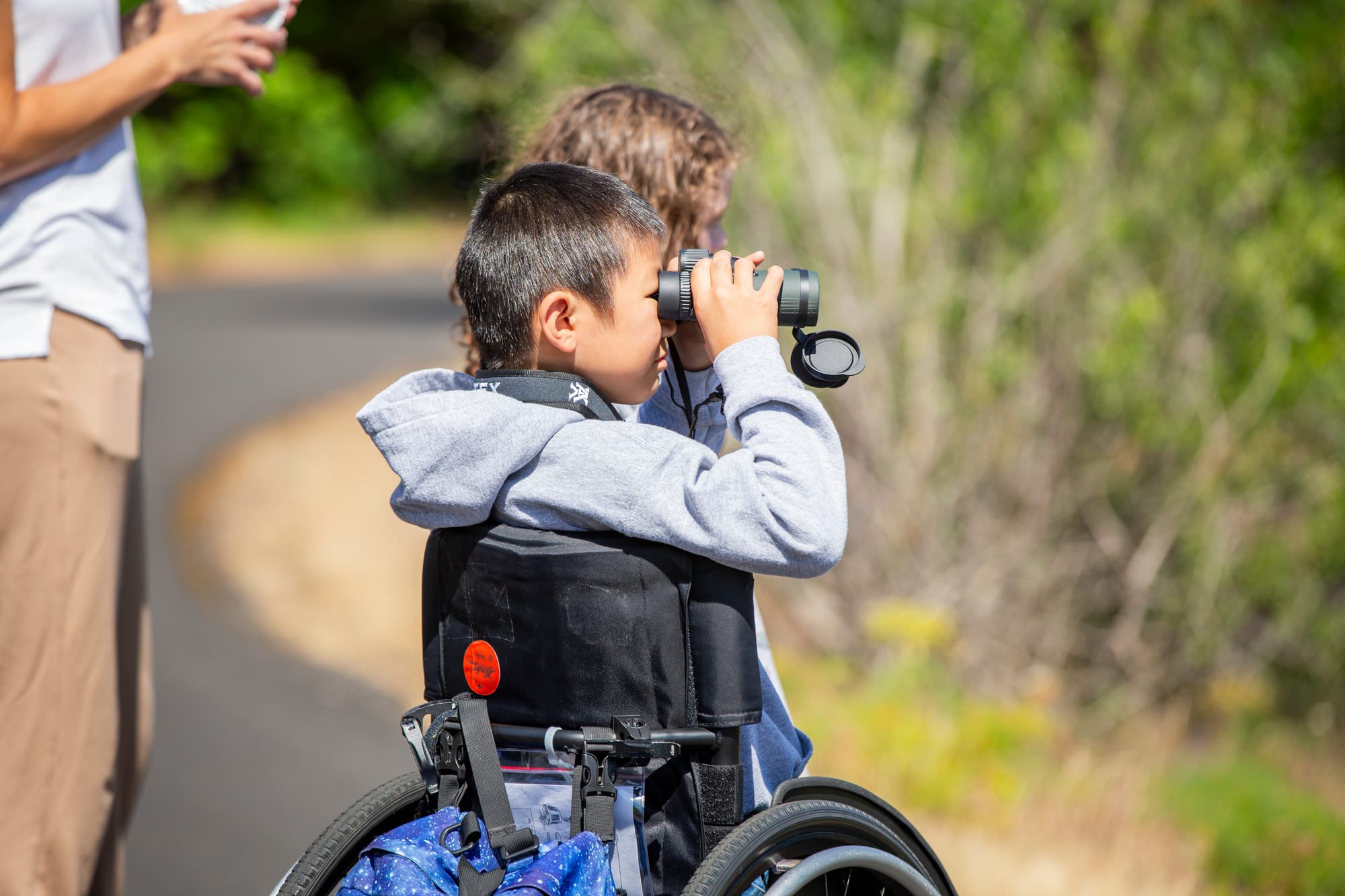 Wheelchair user boy looking through binoculars on Historic Columbia River Highway State Trail