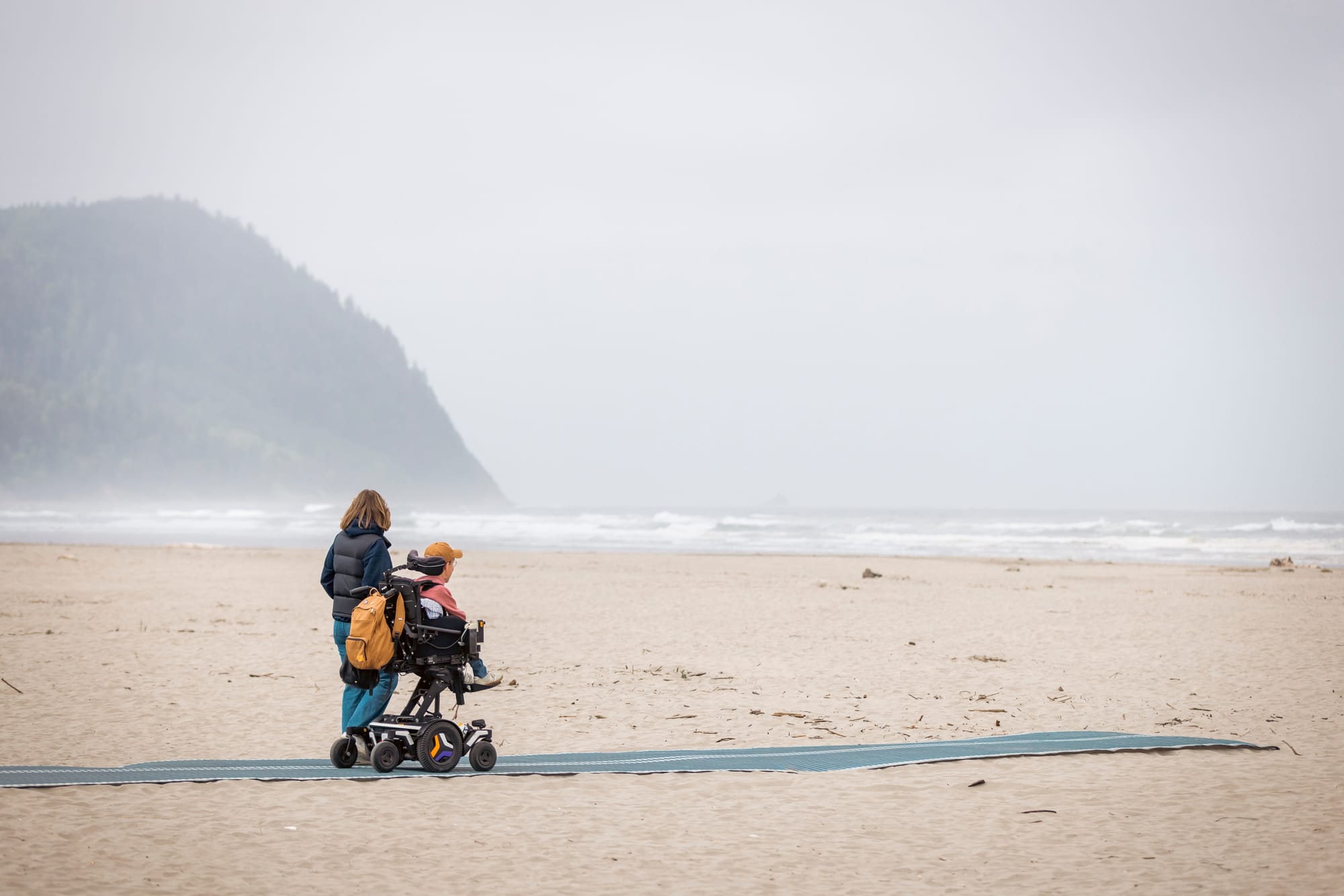Wheelchair user and companion on mobi mats in Seaside, OR