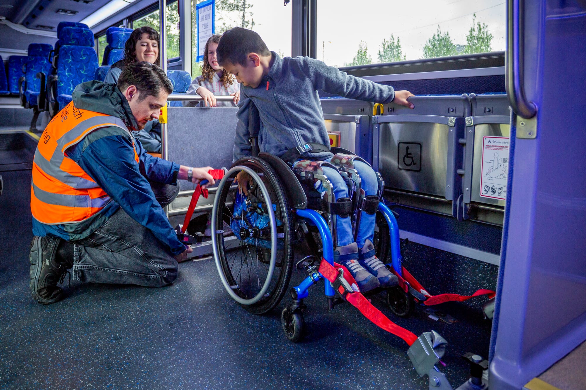 Wheelchair user, a boy, getting secured on an accessible bus