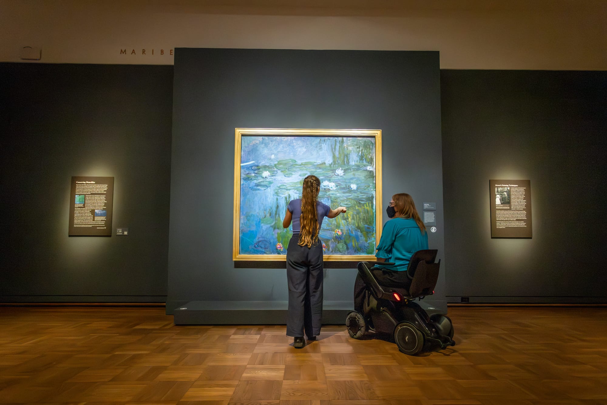 Wheelchair user and deaf lady looking at an art piece at Portland Art Museum