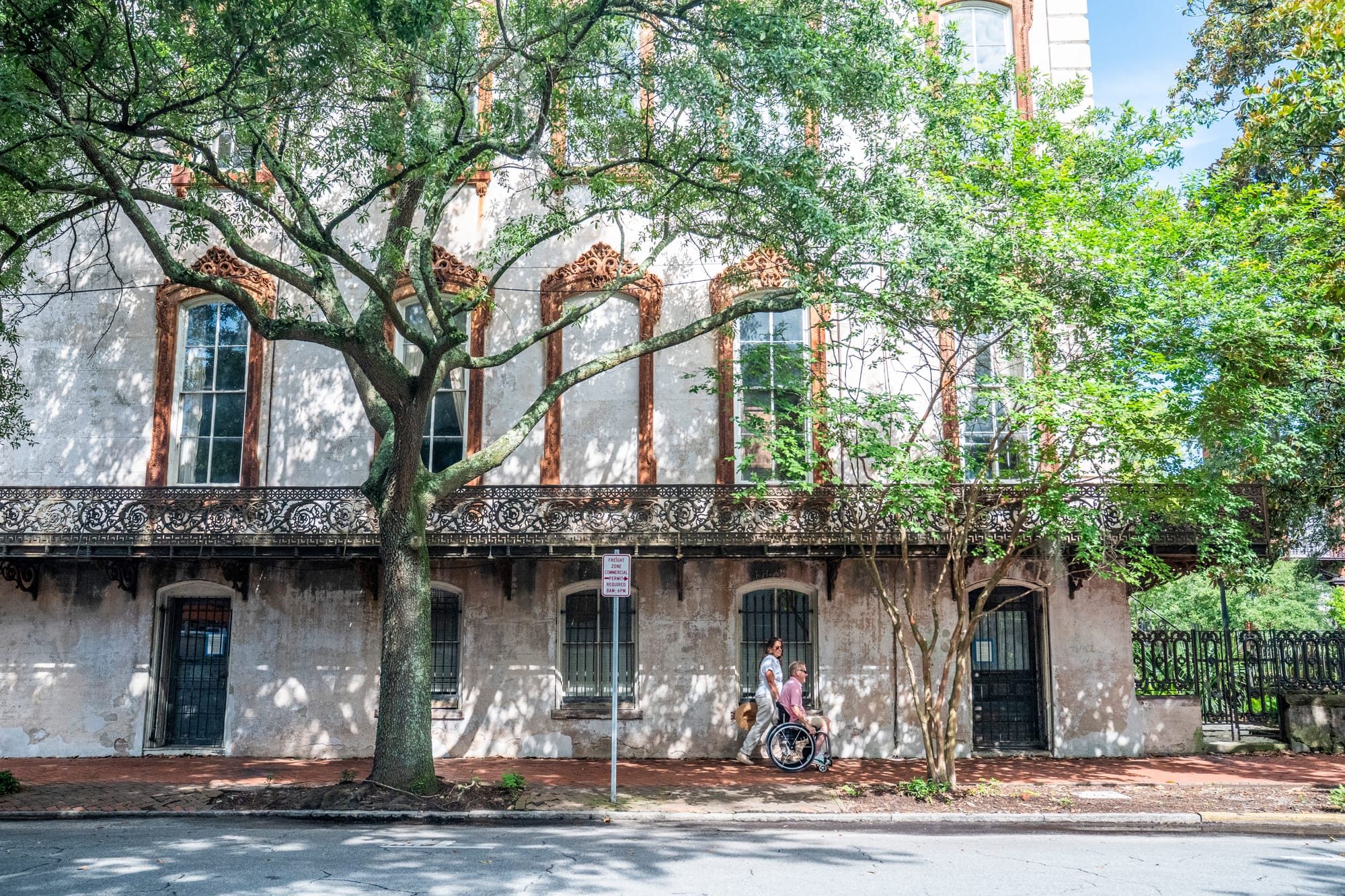 Wheelchair user and companion rolling along the sidewalk in Savannah