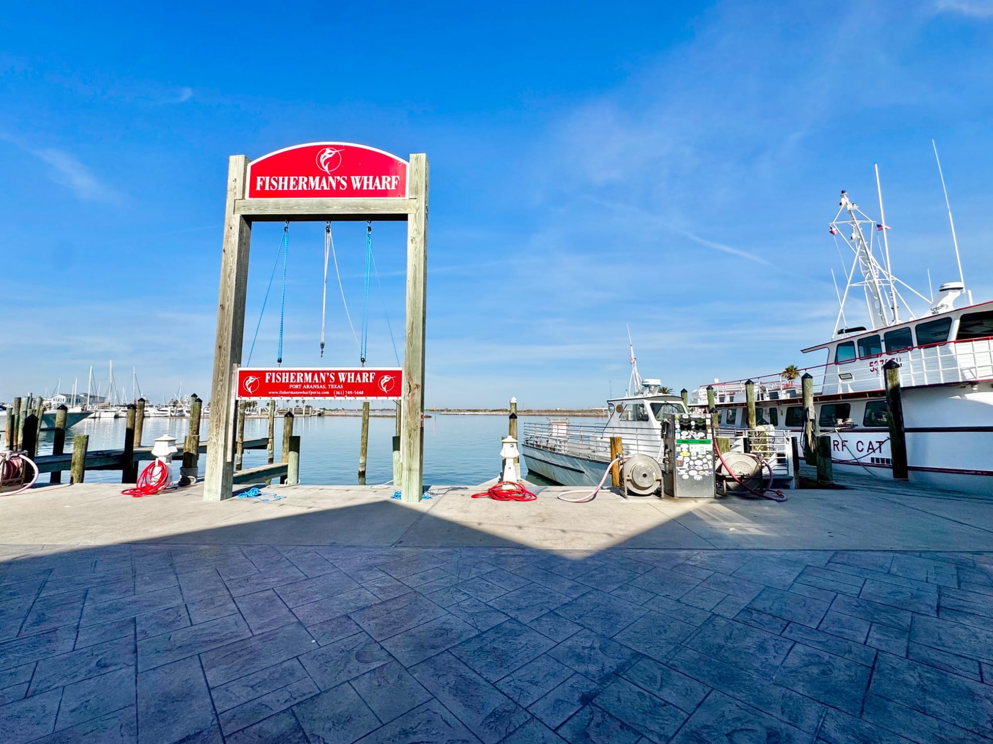 Fisherman's Wharf sign with docks and a boat in Port Aransas