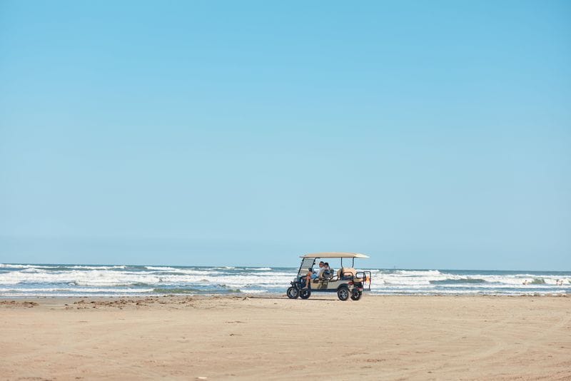 Couple driving a golf cart on the beaches in Port Aransas