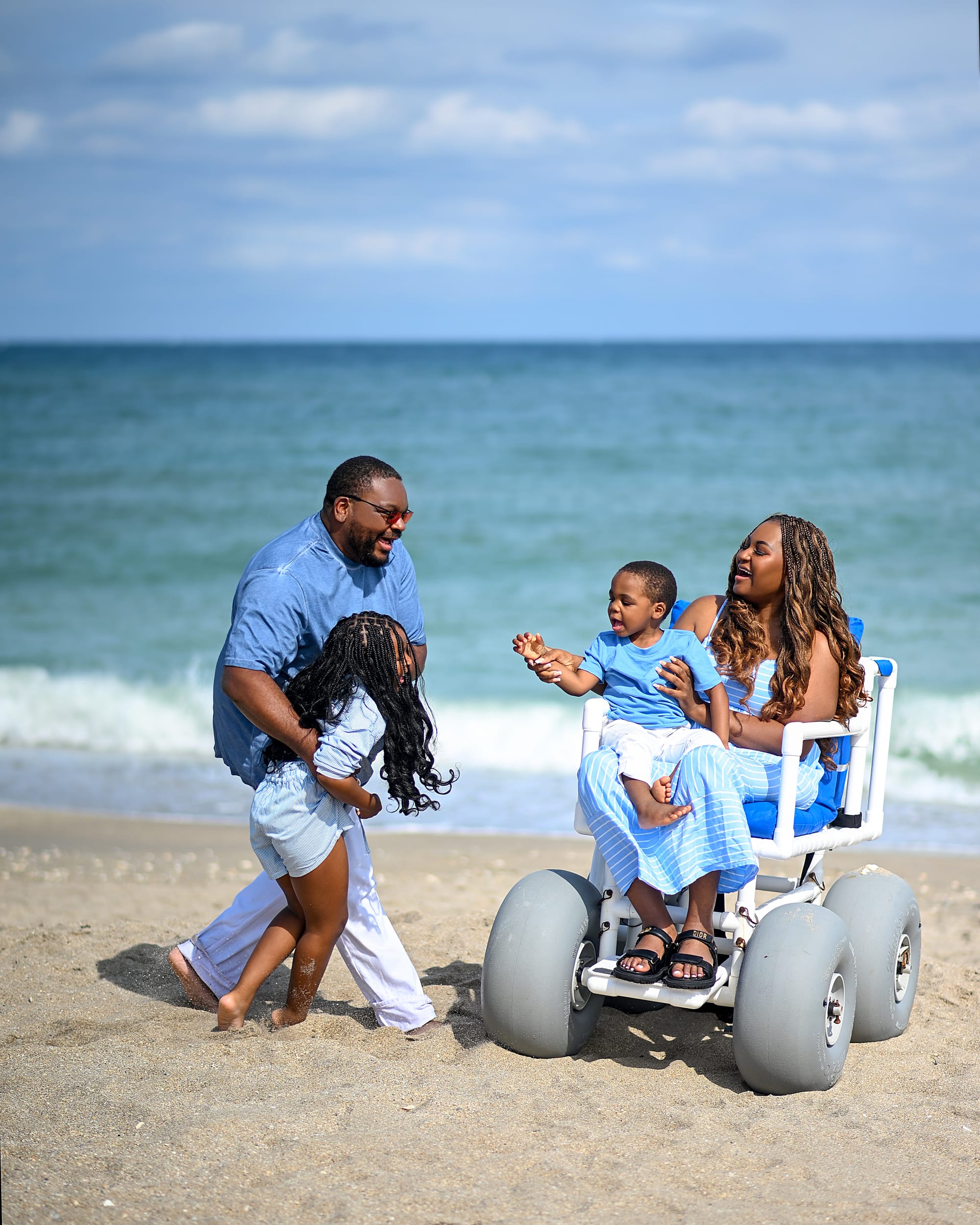 Lizzy, in a beach wheelchair, and her family having fun at the beach in Martin County