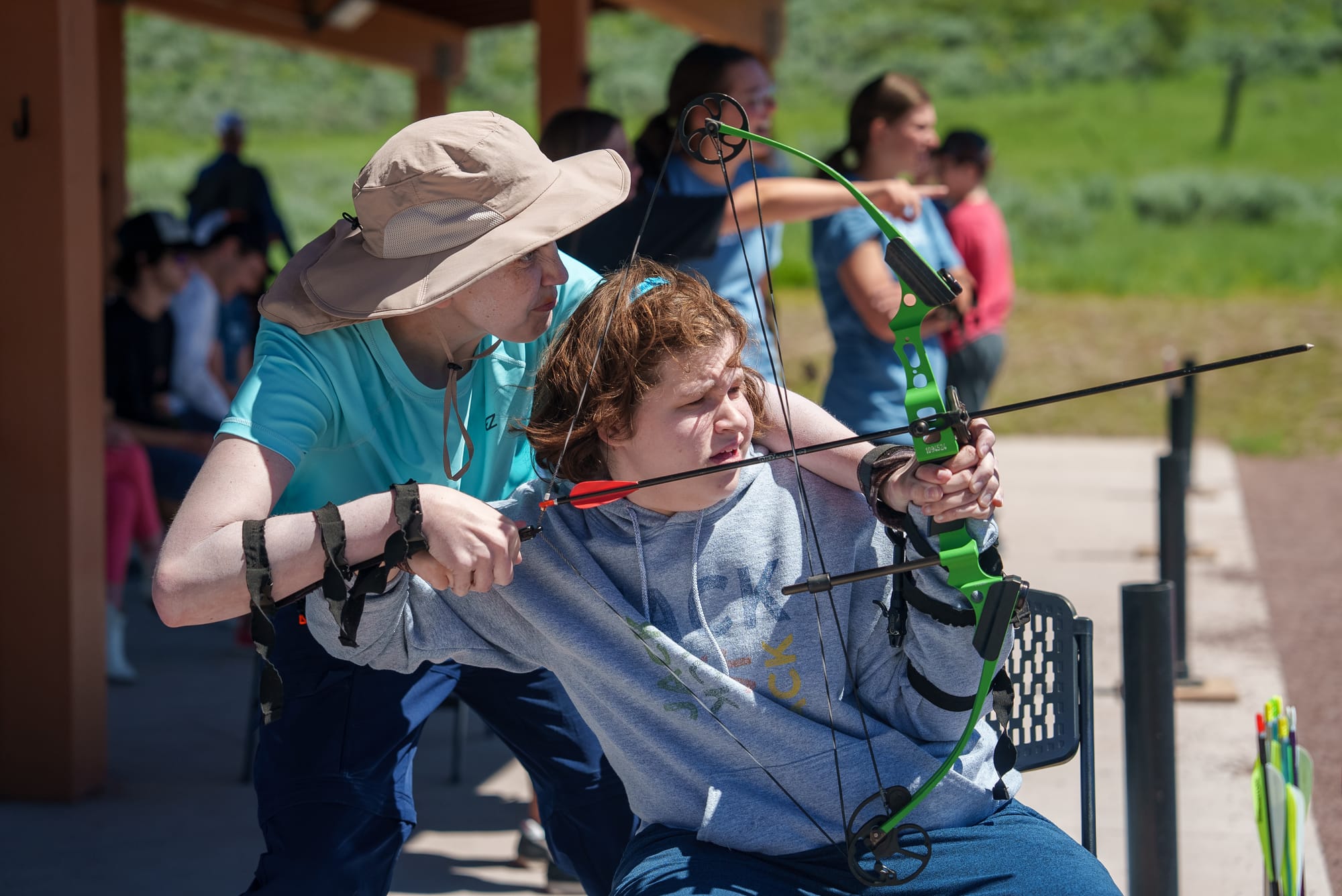 Woman assisting child with adaptive archery 
