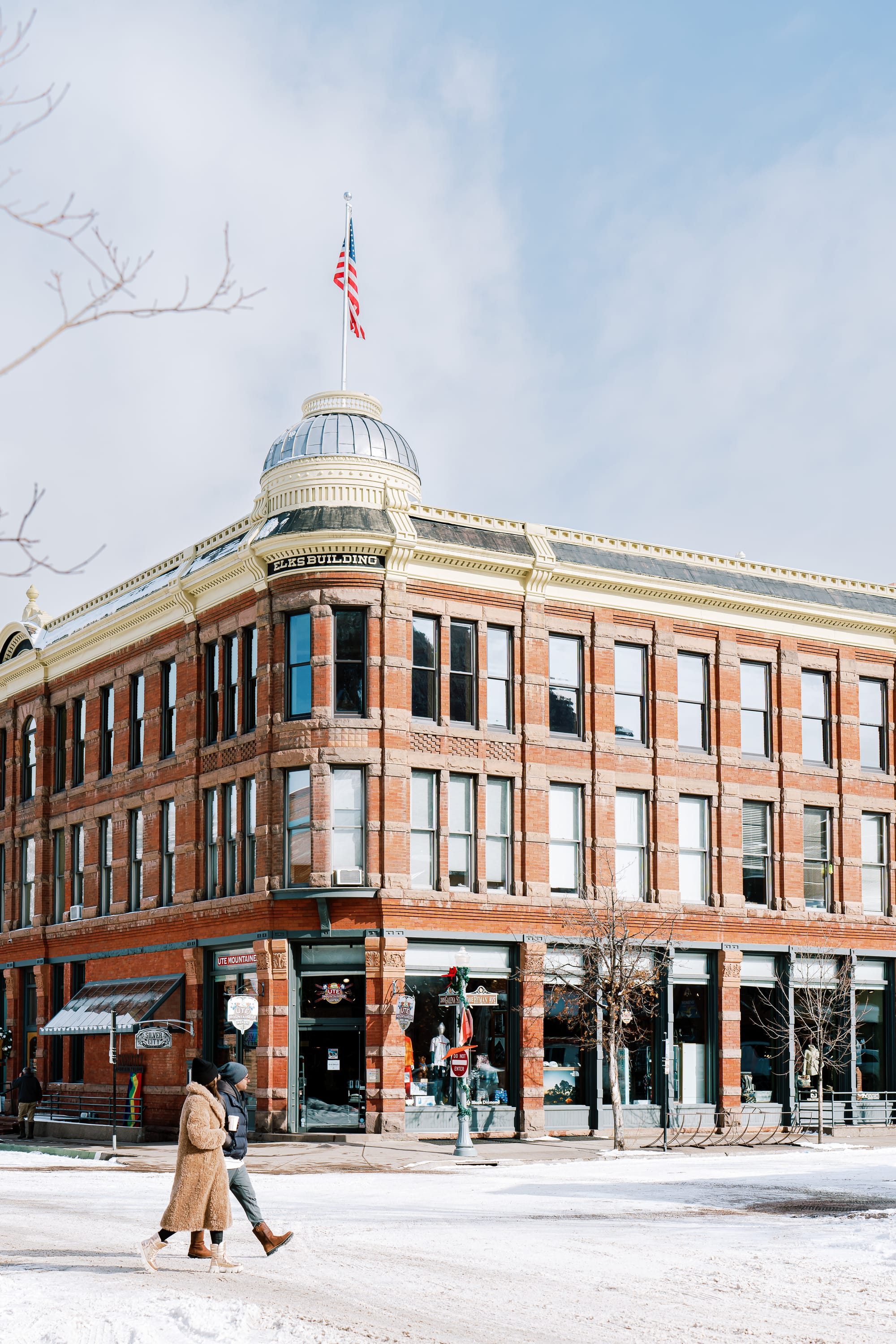 Couple walking across the street in Downtown Aspen, Colorado with snow on the ground