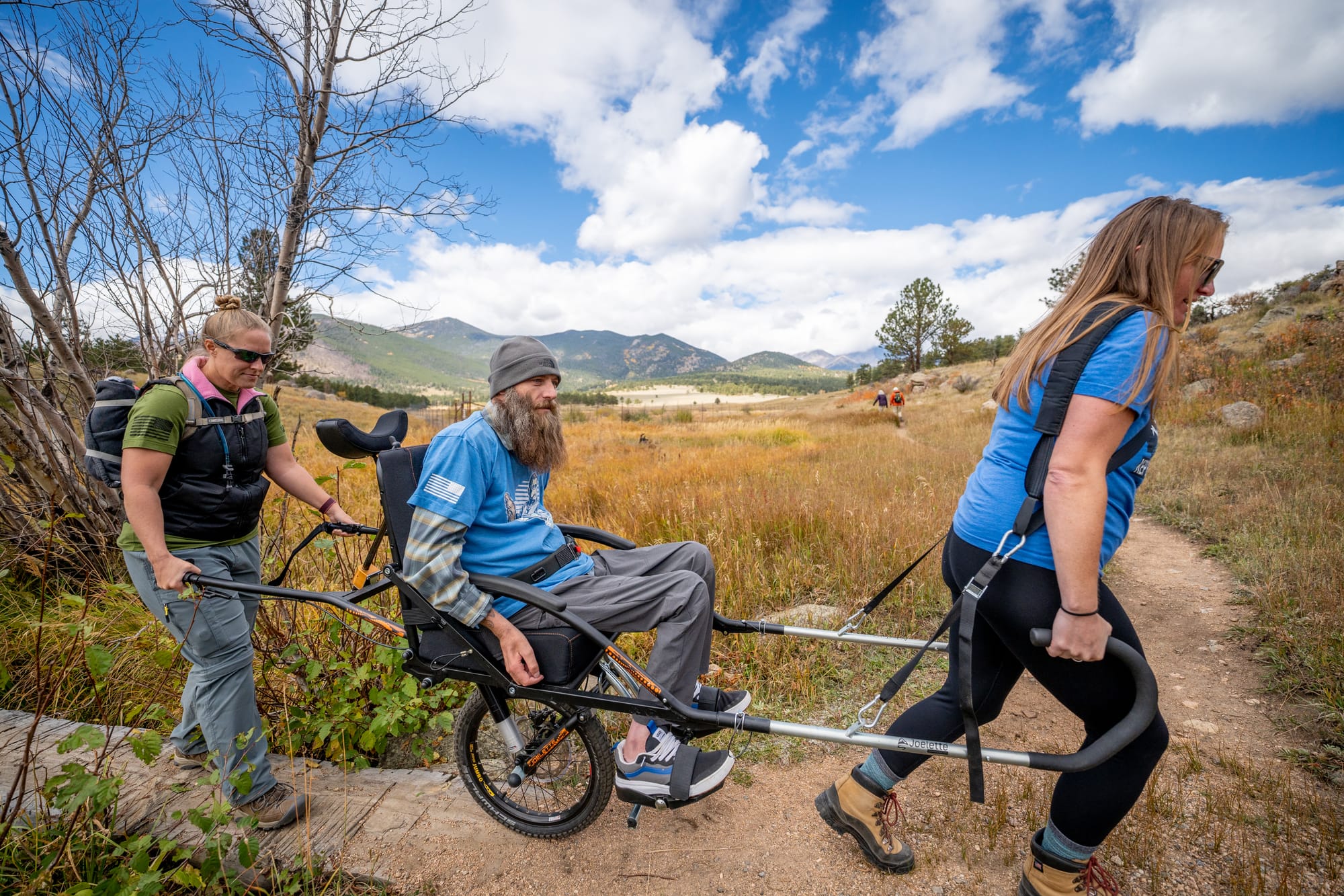 Man in a joelette wheelchair with two companions