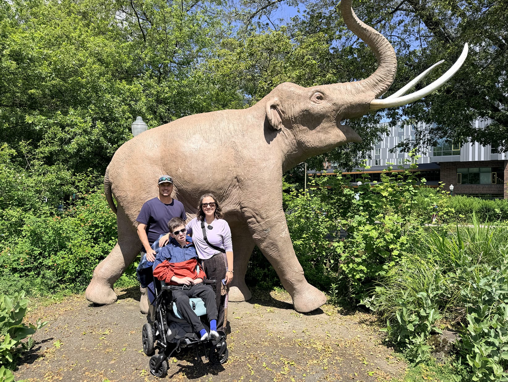 Father, mother, and their wheelchair-user son in front of the elephant statue at Museum of Natural and Cultural History