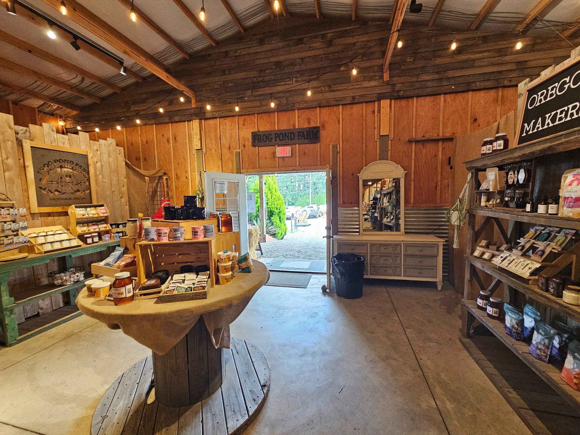 Inside the Frog Pond Farm barn store in Wilsonville, Oregon, with local honey, jams, and Oregon-made goods on wooden shelves and a wide open doorway leading outside