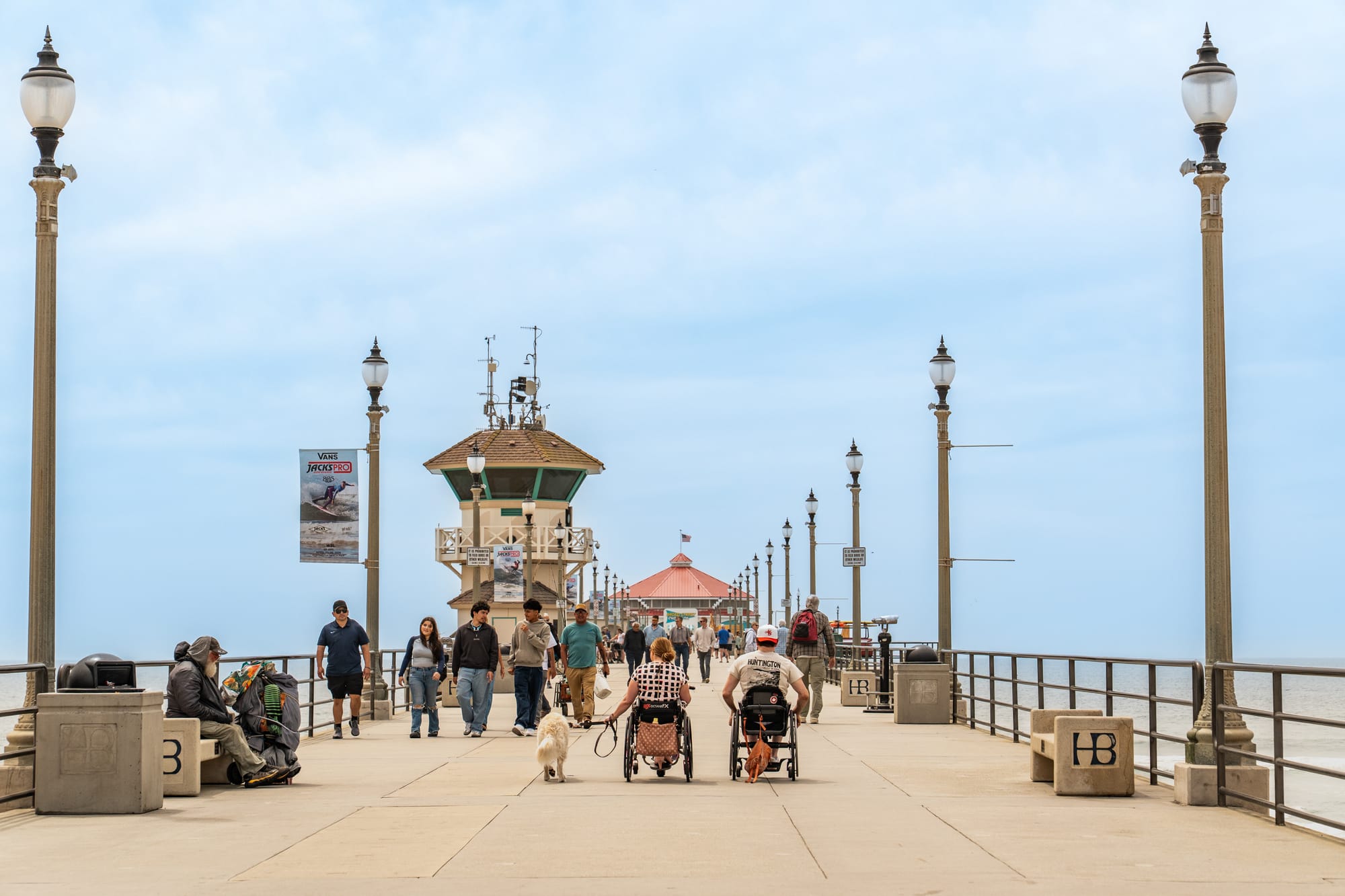 Two wheelchair users and service dog on the accessible, paved Huntington Beach Pier