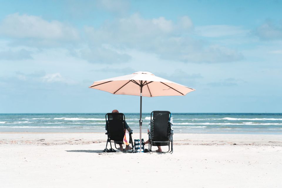 Couple sitting on Corpus Christi beach with chairs and umbrella