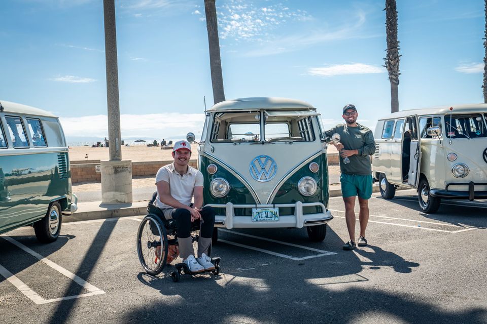 Reese Ketler in his wheelchair in front of a vintage Volkswagen van at Huntington Beach, with his friend