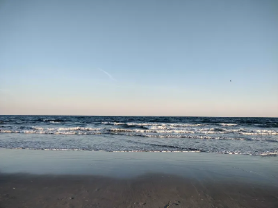 A beach at low tide, early sunrise, with what I think is a helicopter off in the distance.